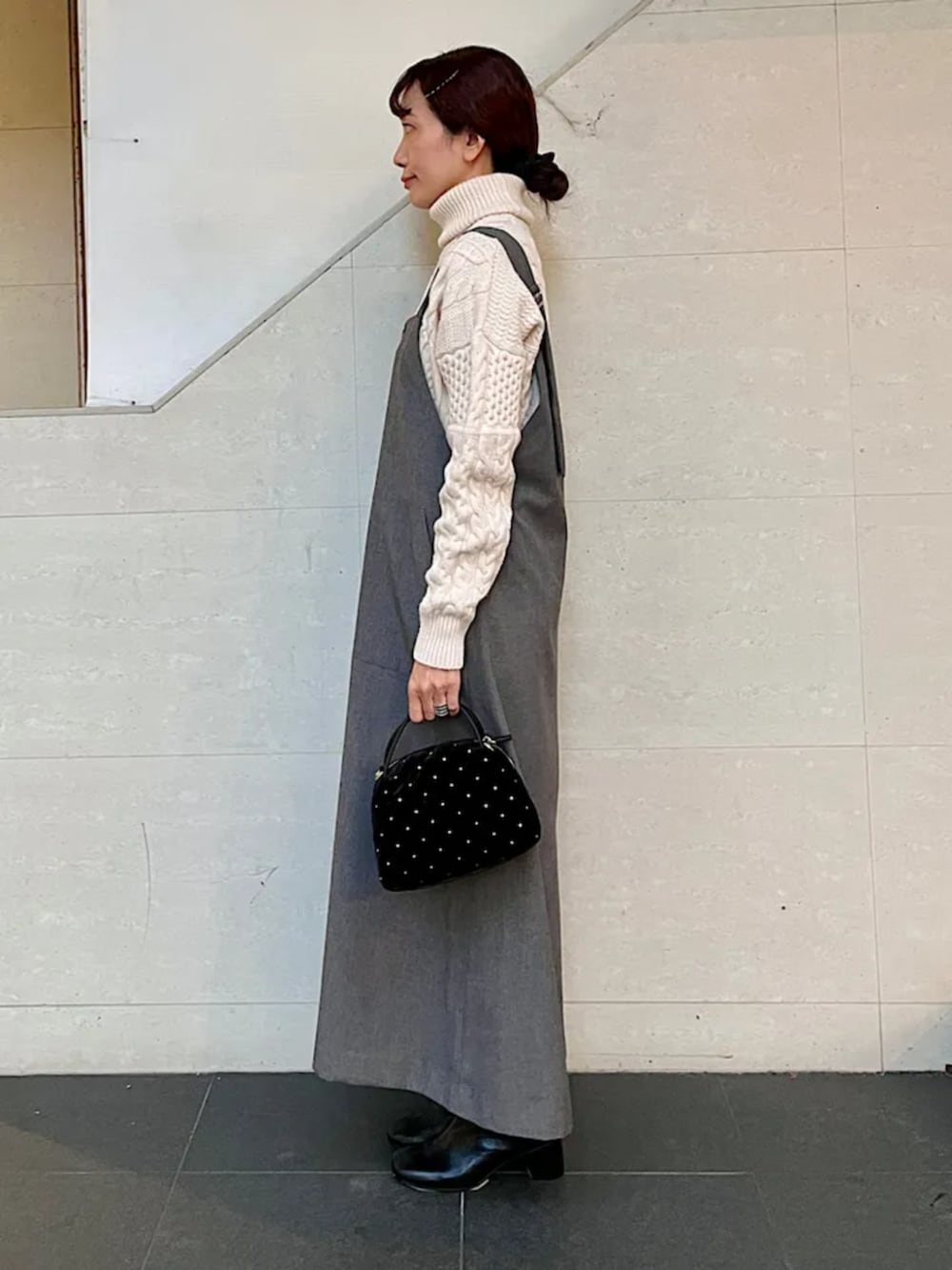 ブラック系のブーツ、ブラック系のショルダーバッグ、ブラウン系のジャンパースカートを着用したレディースの冬コーディネートの2枚目の写真