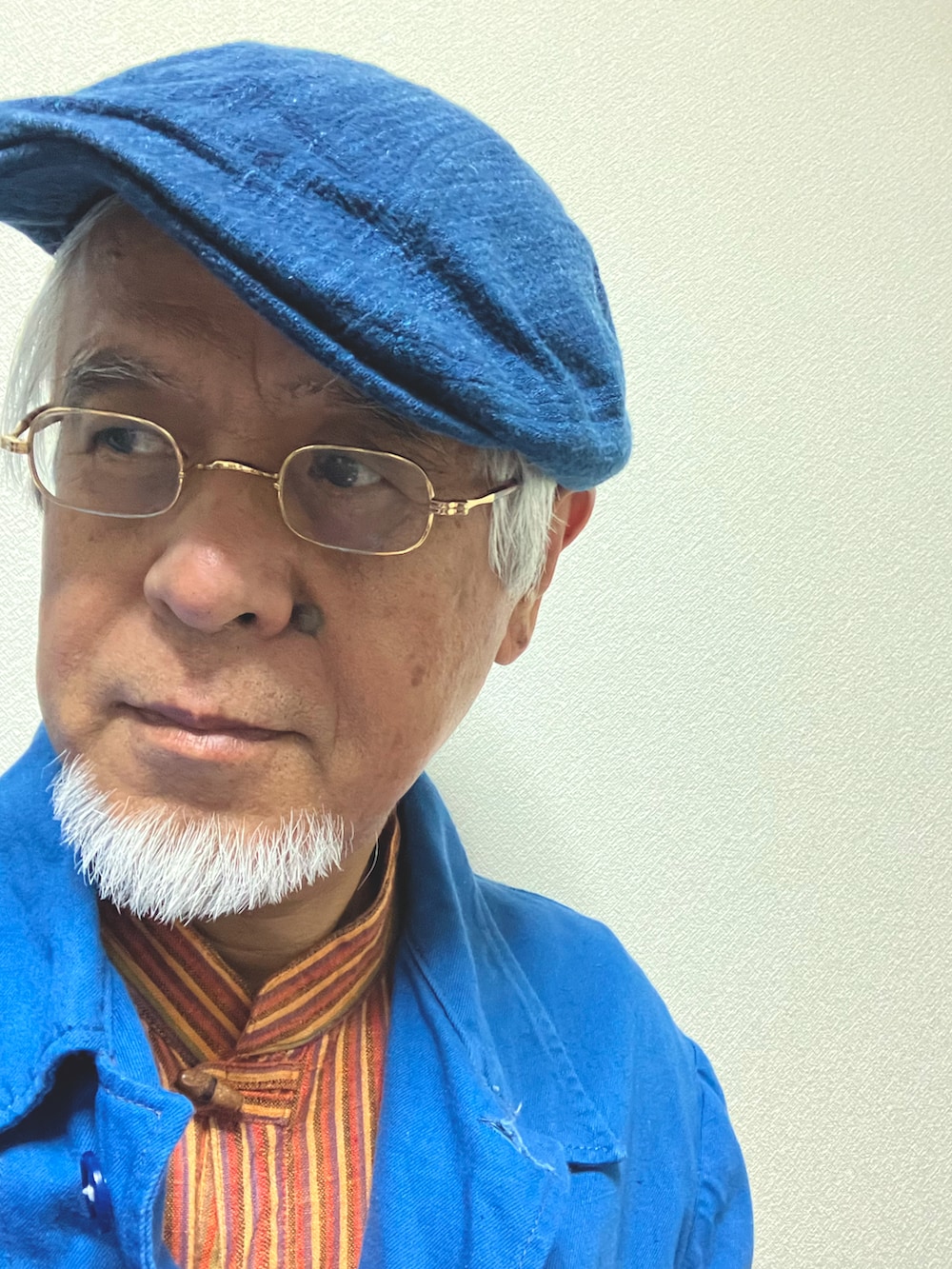 オレンジ系のカバーオール、ブルー系のミリタリージャケット、ブルー系のハンチング/ベレー帽を着用したメンズの秋コーディネートの2枚目の写真