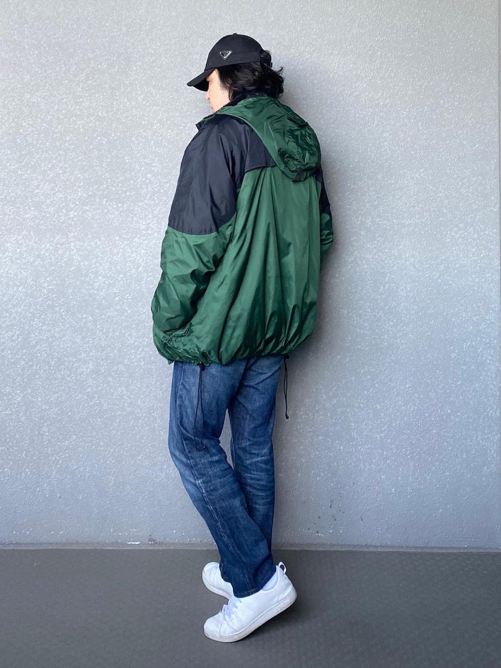 ブルー系のデニムパンツ、ホワイト系のスニーカー、グリーン系のマウンテンパーカーを着用したメンズの冬コーディネートの2枚目の写真