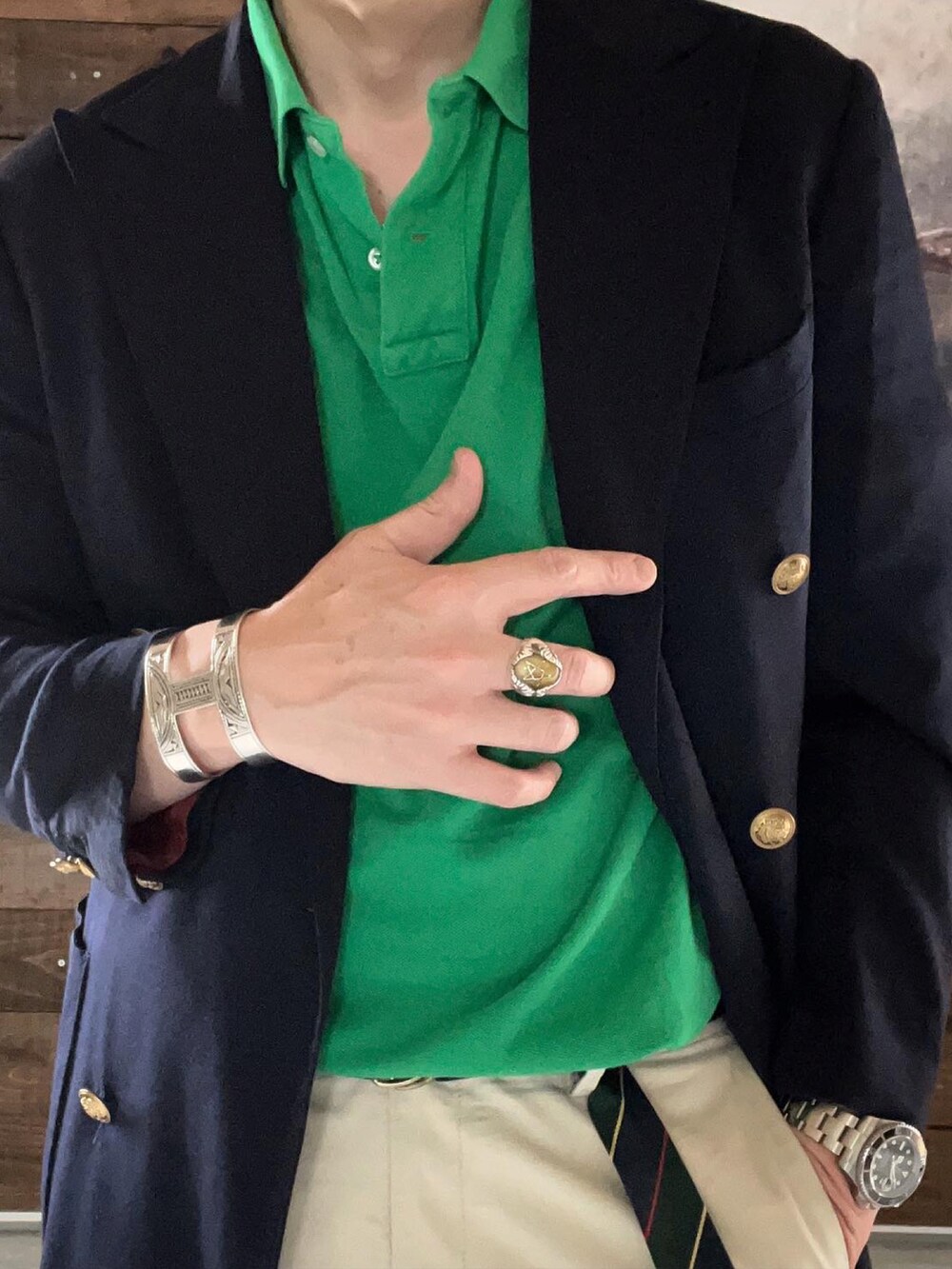 ブラウン系のトートバッグ、ブルー系のテーラードジャケット、グリーン系のポロシャツを着用したメンズの春コーディネートの2枚目の写真