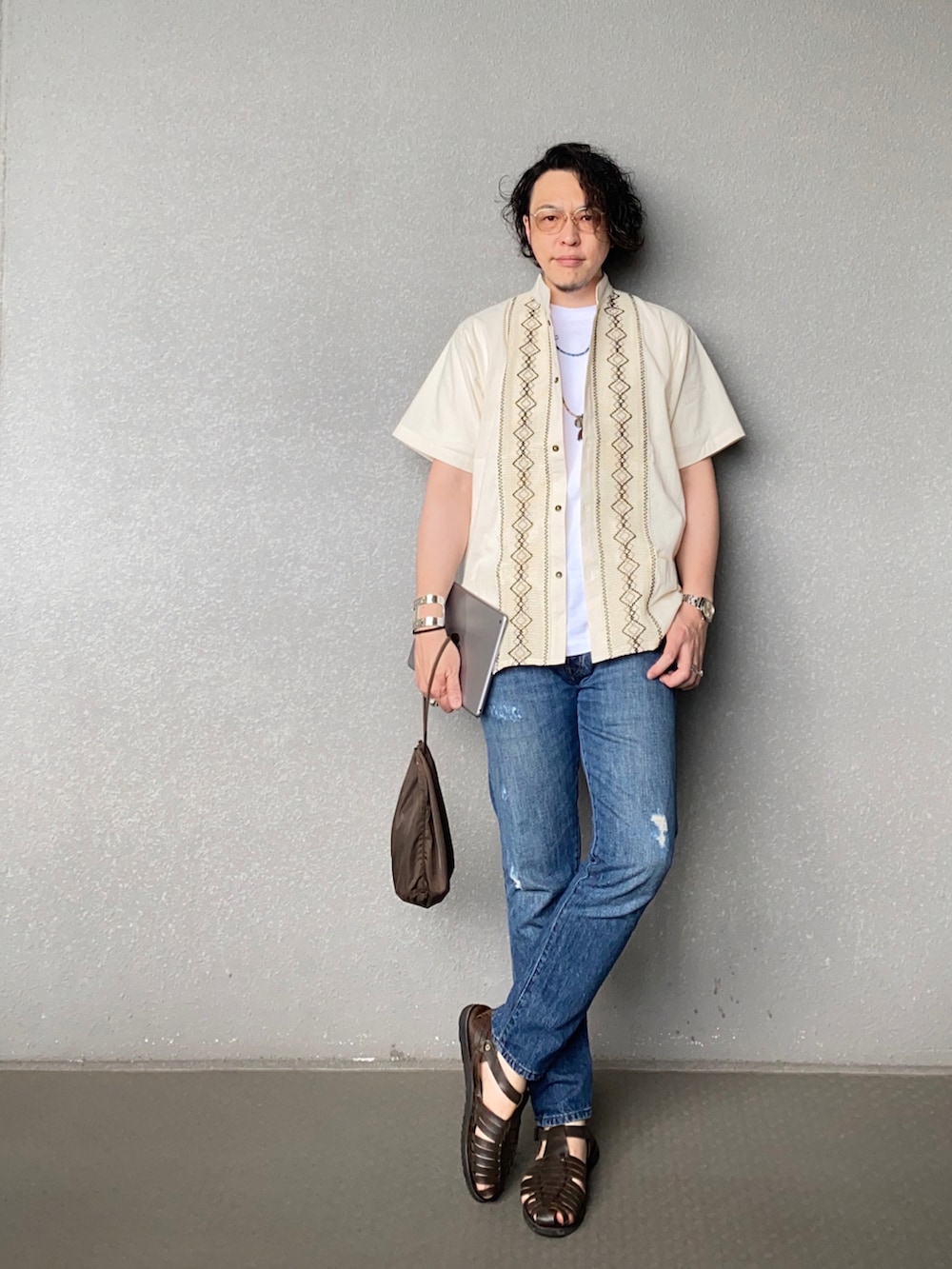 ブルー系のデニムパンツ、ブラウン系のサンダル、ホワイト系のシャツ/ブラウスを着用したメンズの夏コーディネートの2枚目の写真