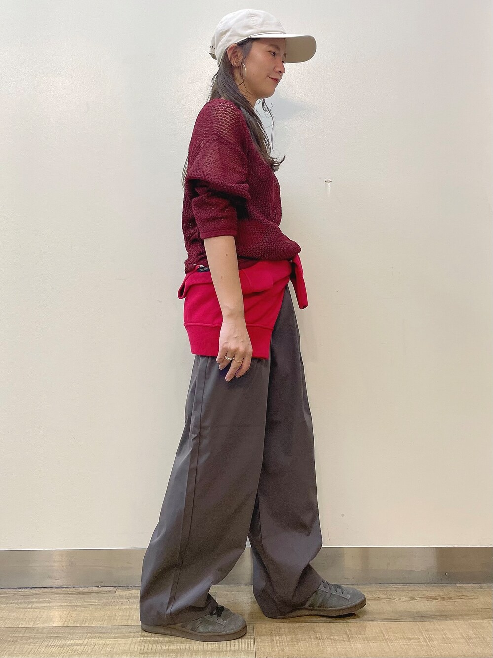 レッド系のニット/セーター、グレー系のその他パンツ、ベージュ系のキャップを着用したレディースの秋コーディネートの2枚目の写真