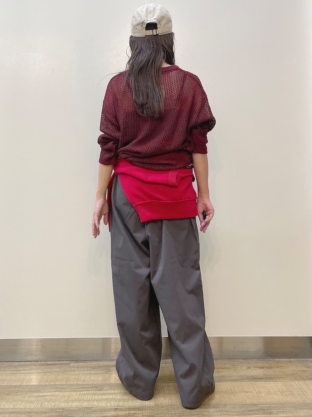 レッド系のニット/セーター、グレー系のその他パンツ、ベージュ系のキャップを着用したレディースの秋コーディネートの3枚目の写真