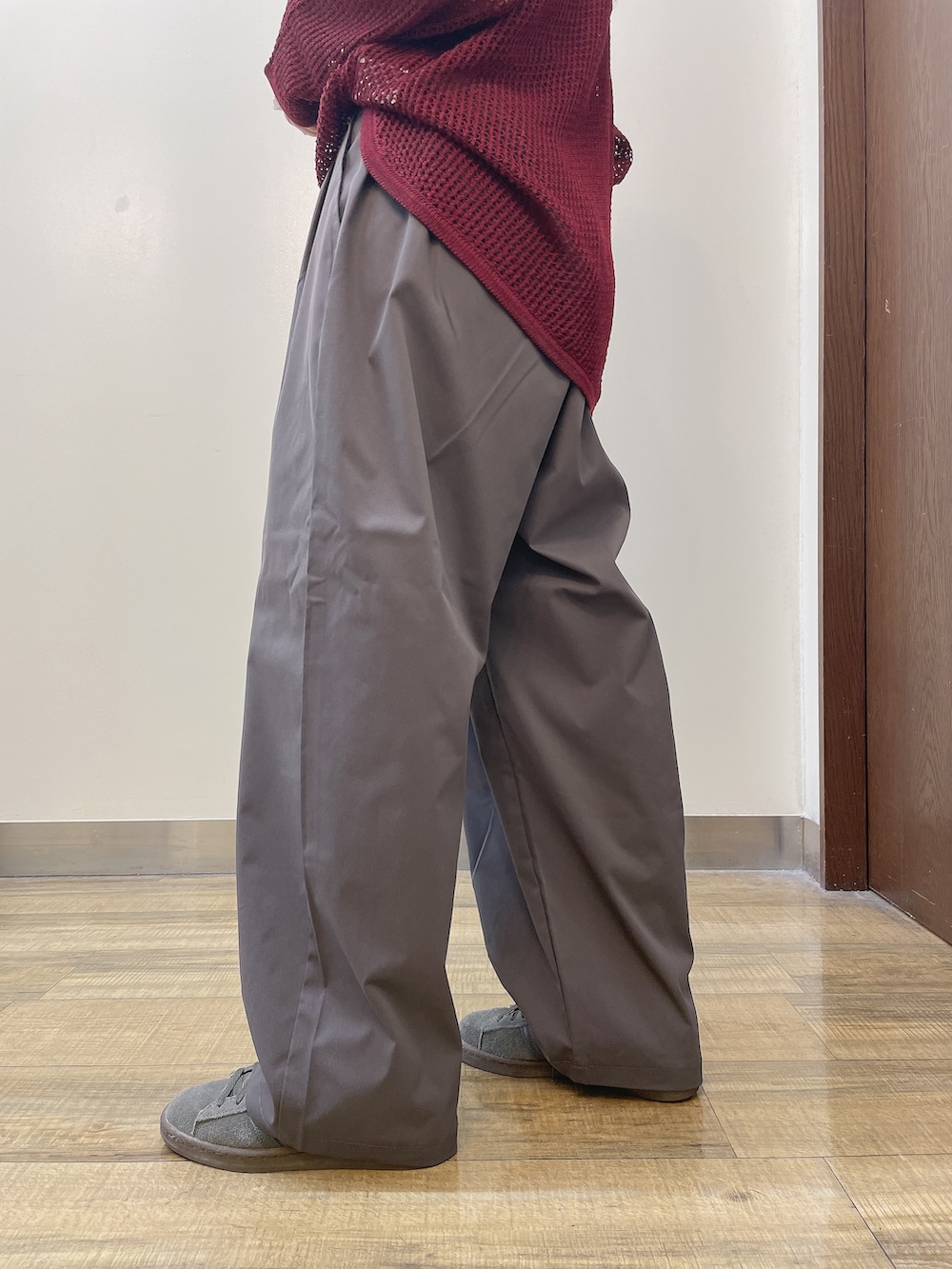 レッド系のニット/セーター、グレー系のその他パンツ、ベージュ系のキャップを着用したレディースの秋コーディネートの6枚目の写真