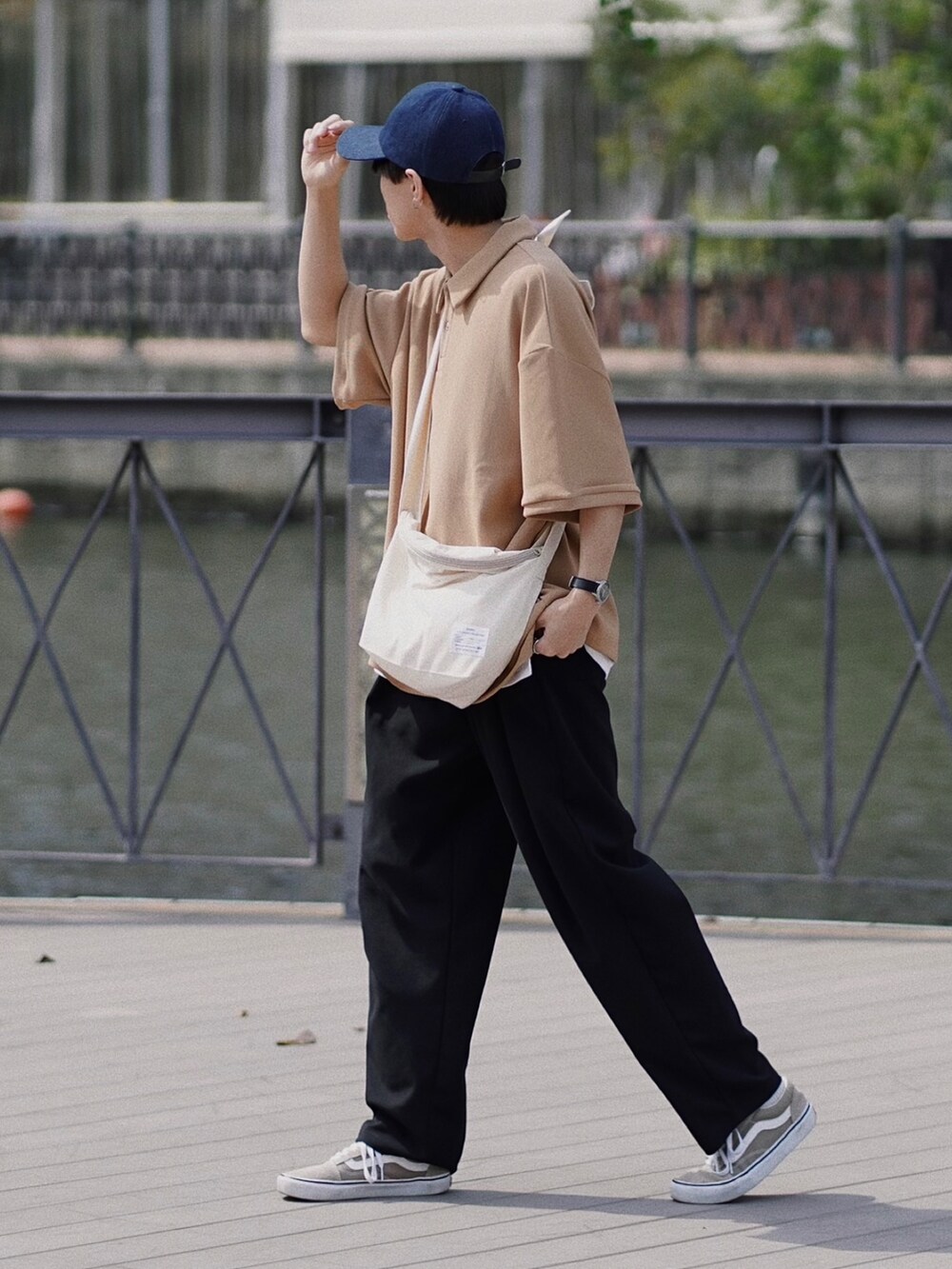 ベージュ系のポロシャツ、ベージュ系のショルダーバッグ、ブラック系のその他パンツを着用したメンズの春コーディネートの2枚目の写真