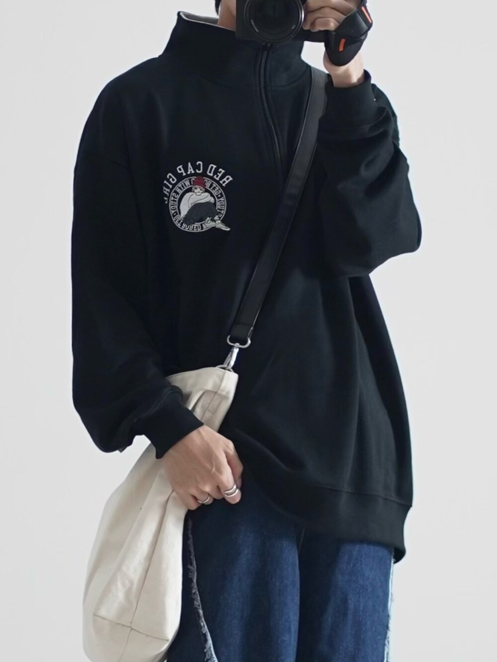 ホワイト系のトートバッグ、ブルー系のデニムパンツ、ブラック系のスニーカーを着用したメンズの秋コーディネートの2枚目の写真