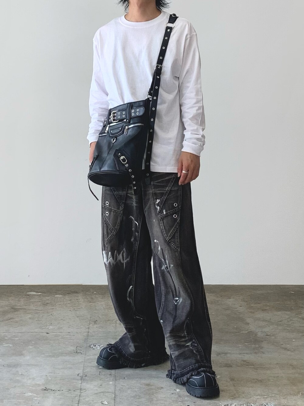 ブラック系のスニーカー、ホワイト系のTシャツ/カットソー、ブラック系のデニムパンツを着用したメンズの秋コーディネートの2枚目の写真
