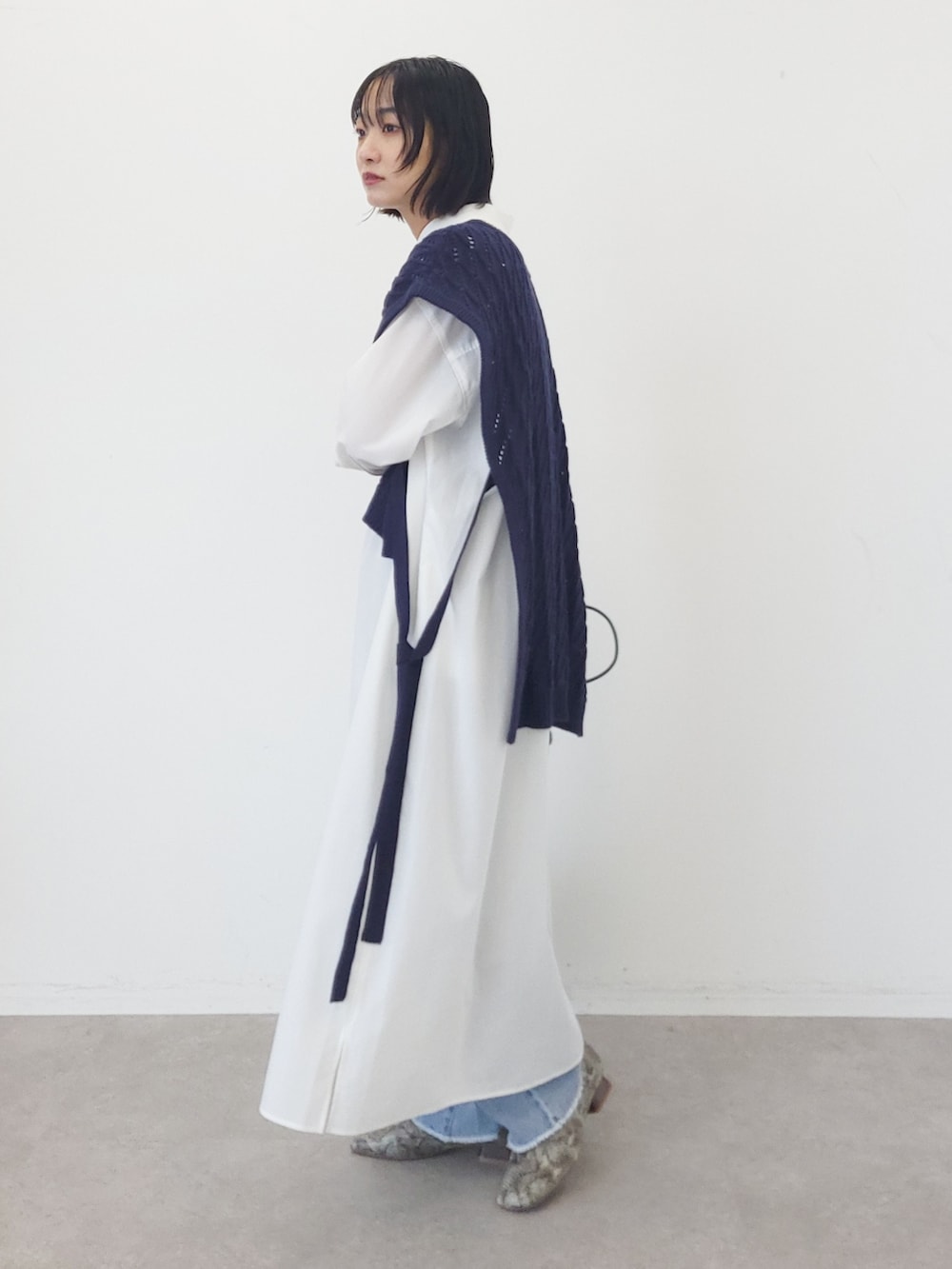 ブルー系のベスト、ホワイト系のワンピース、ブルー系のデニムパンツを着用したレディースの夏コーディネートの2枚目の写真