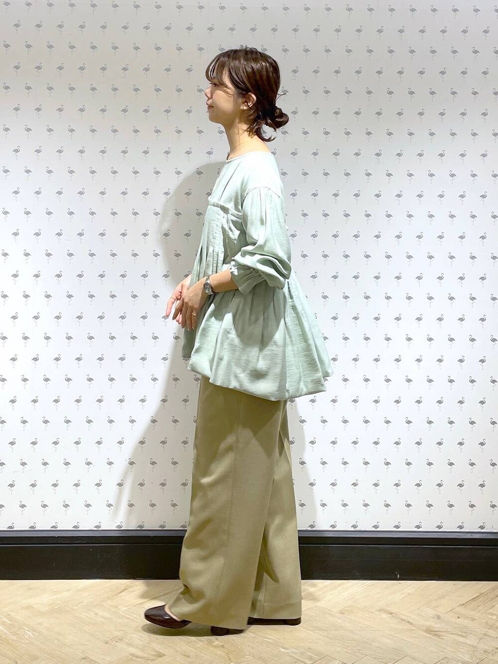 ベージュ系のスラックス、グリーン系のシャツ/ブラウス、レッド系のパンプスを着用したレディースの冬コーディネートの4枚目の写真