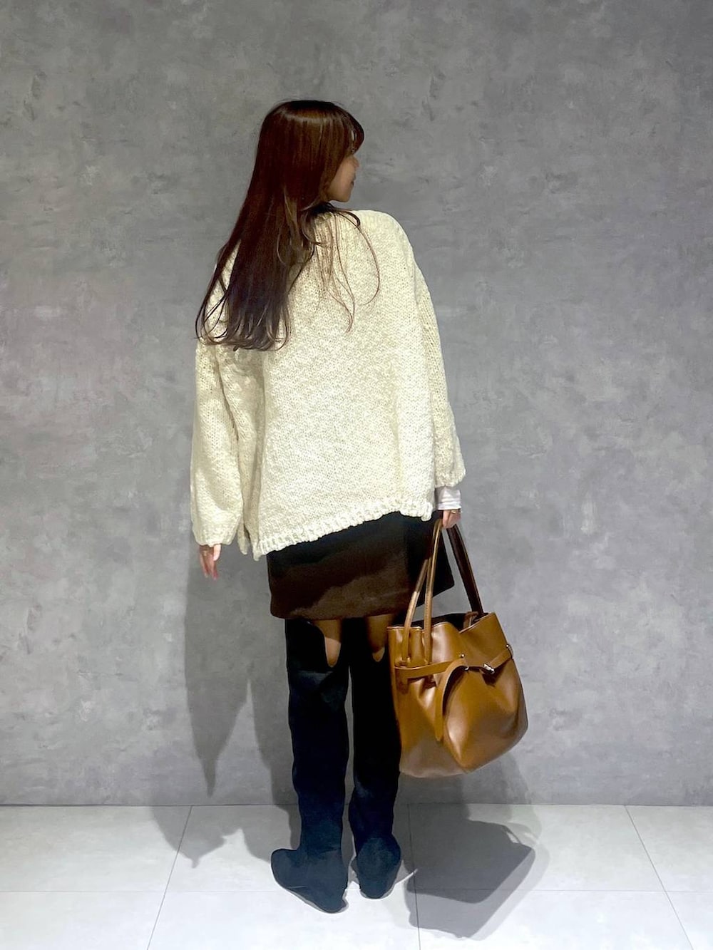 ブラウン系のスカート、ホワイト系のTシャツ/カットソー、ブラック系のブーツを着用したレディースの秋コーディネートの3枚目の写真