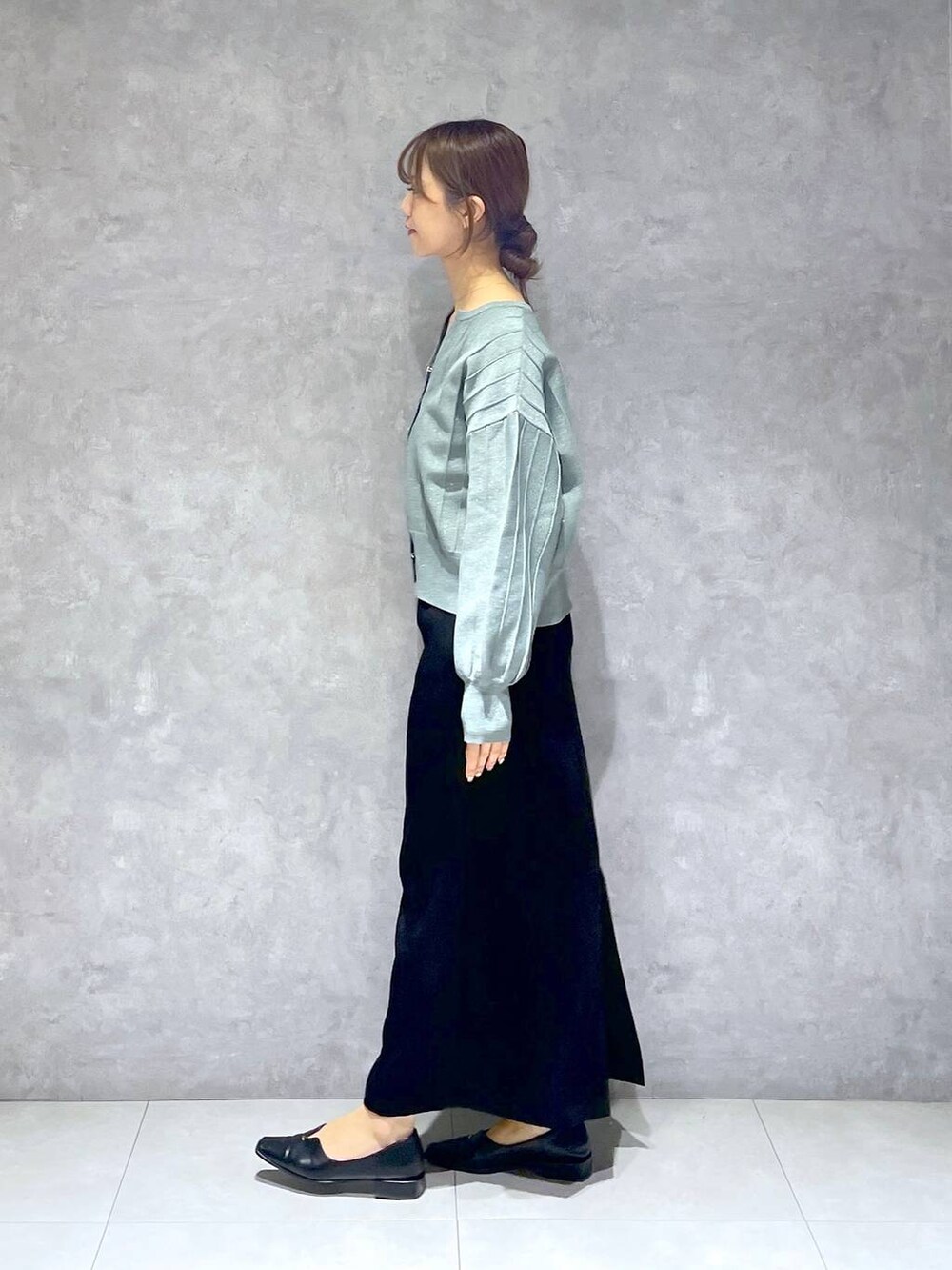 グリーン系のカーディガン/ボレロ、ブラック系のスカートを着用したレディースの春コーディネートの3枚目の写真