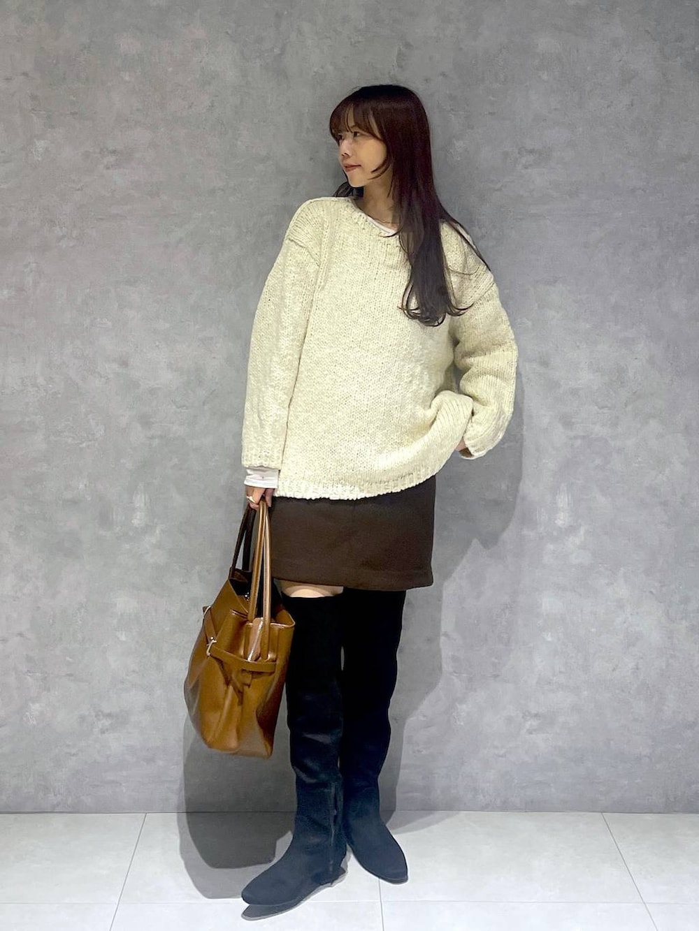 ブラウン系のスカート、ホワイト系のTシャツ/カットソー、ブラック系のブーツを着用したレディースの秋コーディネートの2枚目の写真