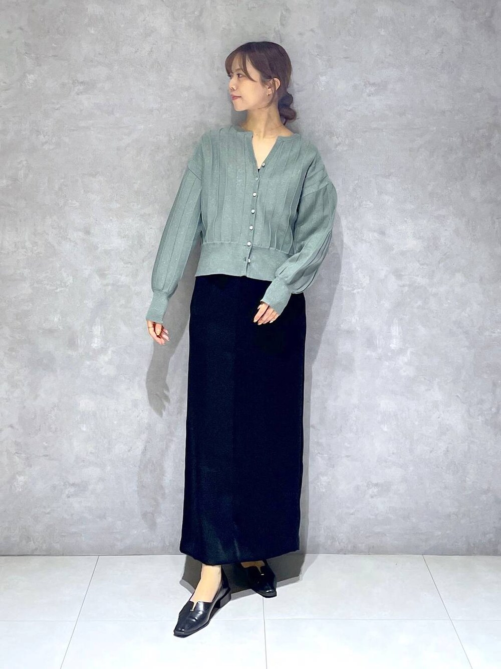 グリーン系のカーディガン/ボレロ、ブラック系のスカートを着用したレディースの春コーディネートの2枚目の写真