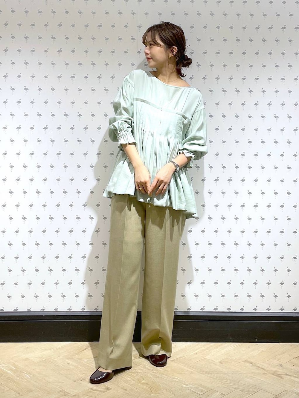 ベージュ系のスラックス、グリーン系のシャツ/ブラウス、レッド系のパンプスを着用したレディースの冬コーディネートの2枚目の写真