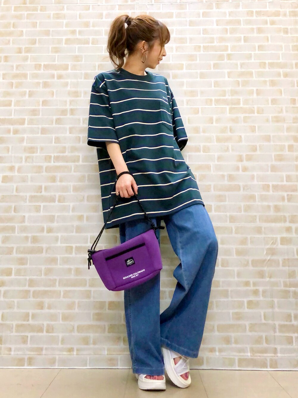 グリーン系のTシャツ/カットソー、ブルー系のデニムパンツ、パープル系のショルダーバッグを着用したレディースの春コーディネートの2枚目の写真