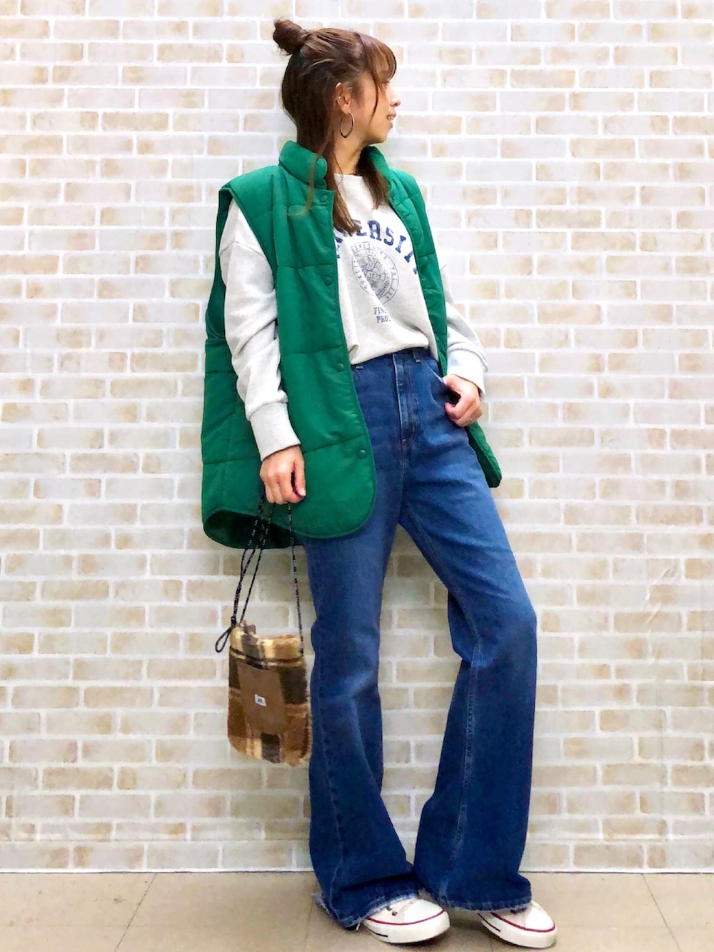 グリーン系のベスト、ブルー系のデニムパンツ、ベージュ系のショルダーバッグを着用したレディースの秋コーディネートの2枚目の写真