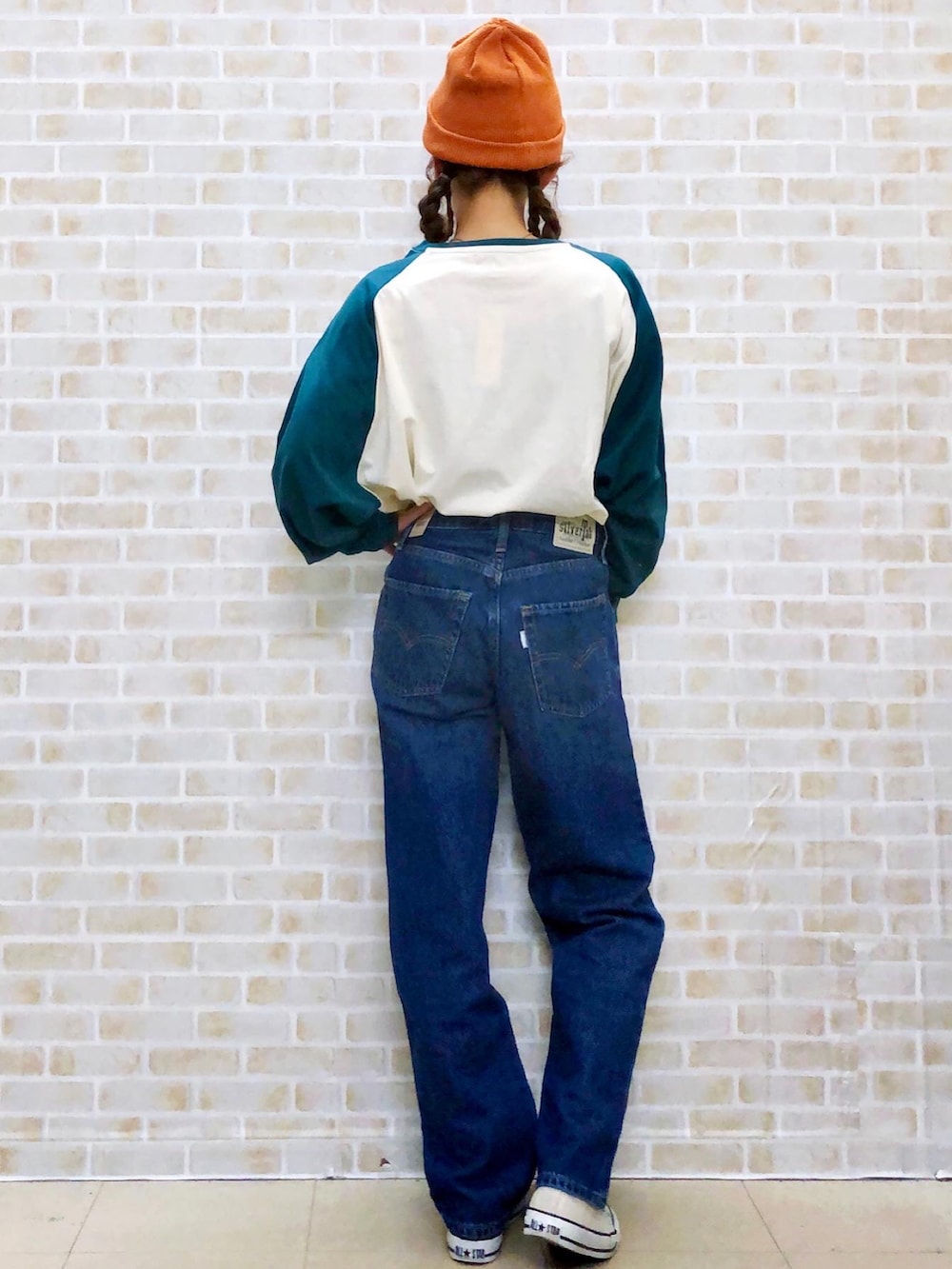 グリーン系のTシャツ/カットソー、ブルー系のデニムパンツ、グレー系のスニーカーを着用したレディースの秋コーディネートの3枚目の写真