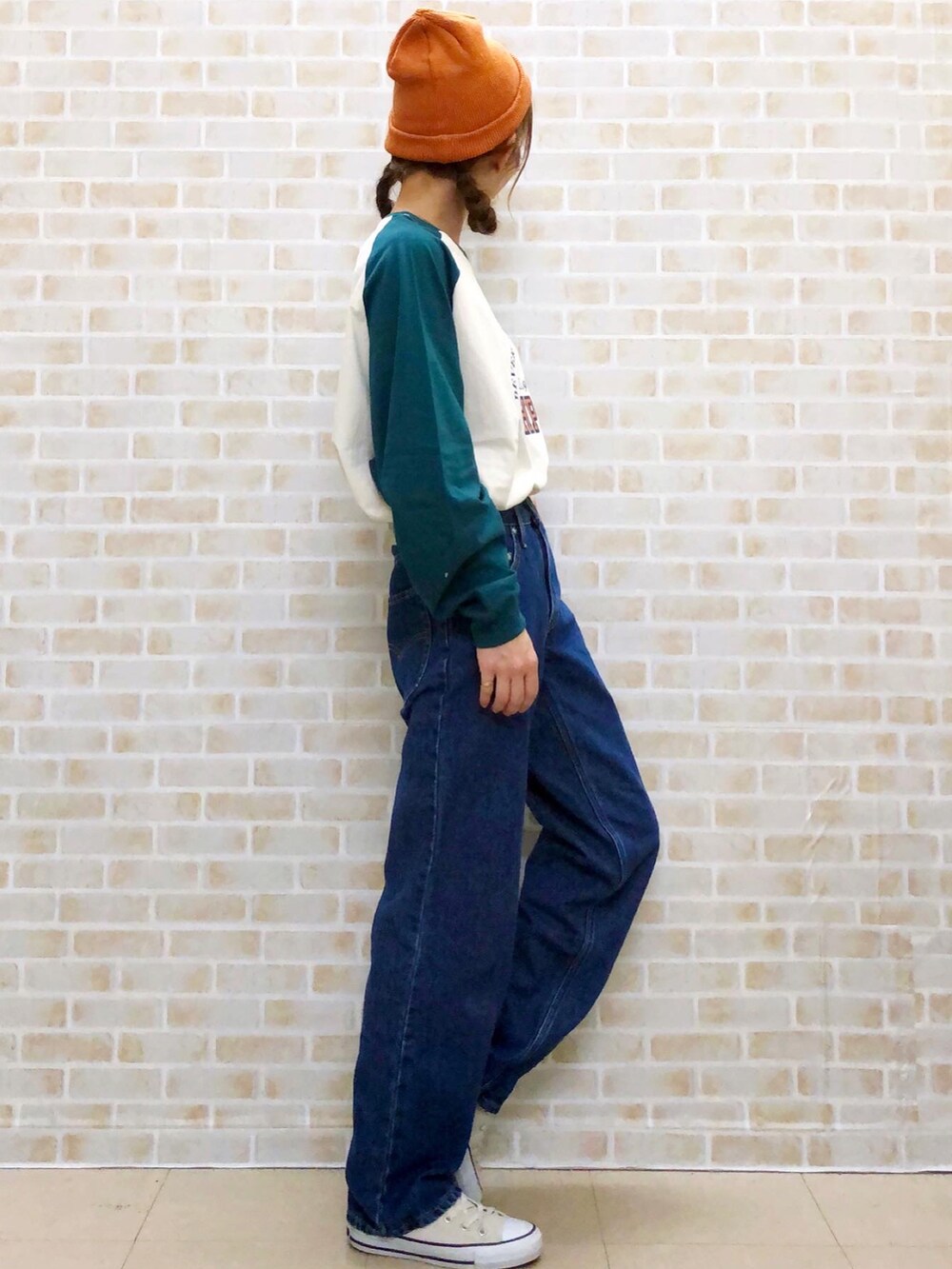 グリーン系のTシャツ/カットソー、ブルー系のデニムパンツ、グレー系のスニーカーを着用したレディースの秋コーディネートの2枚目の写真