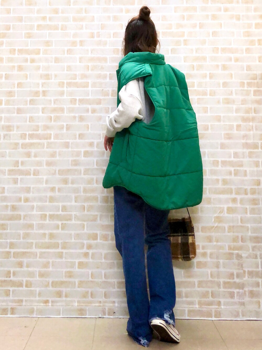 グリーン系のベスト、ブルー系のデニムパンツ、ベージュ系のショルダーバッグを着用したレディースの秋コーディネートの4枚目の写真