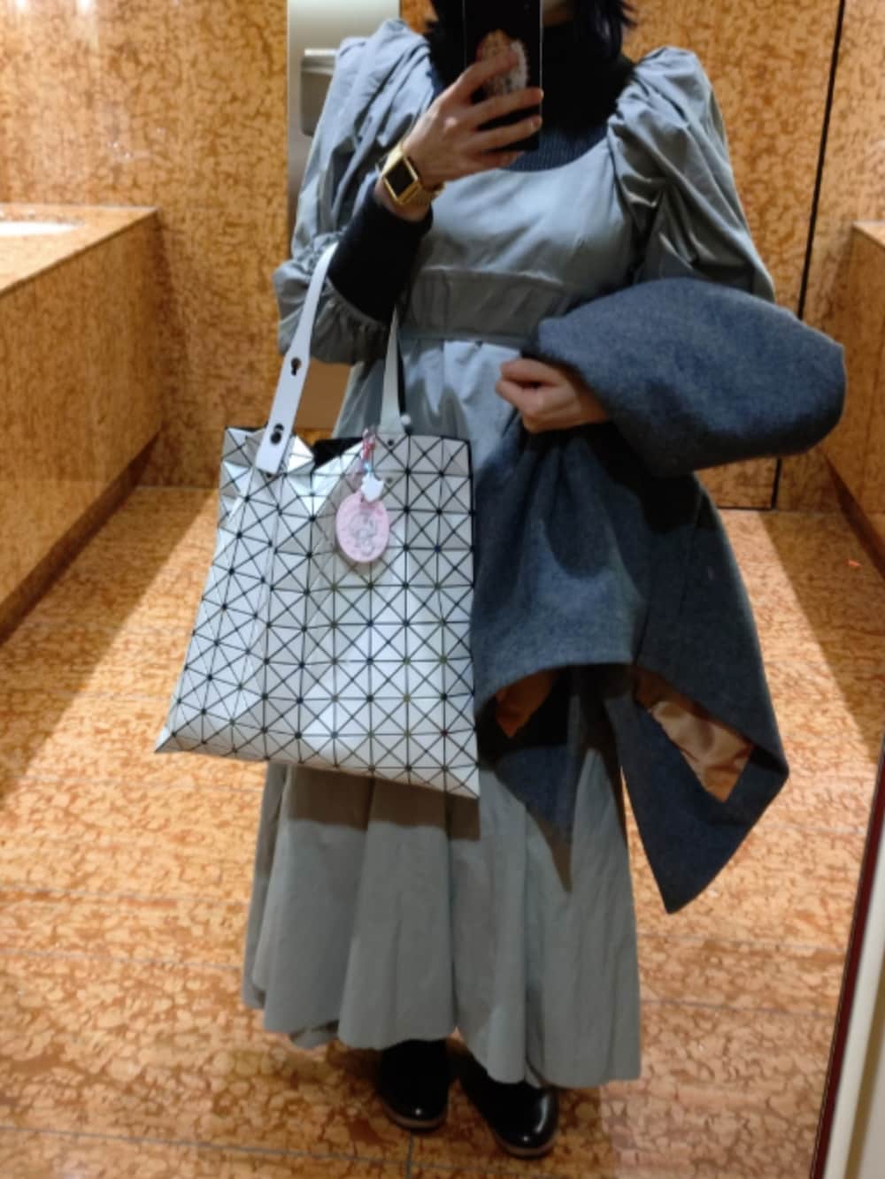 ブラック系のワンピース、グレー系のピーコート、ホワイト系のトートバッグを着用したレディースの冬コーディネートの2枚目の写真