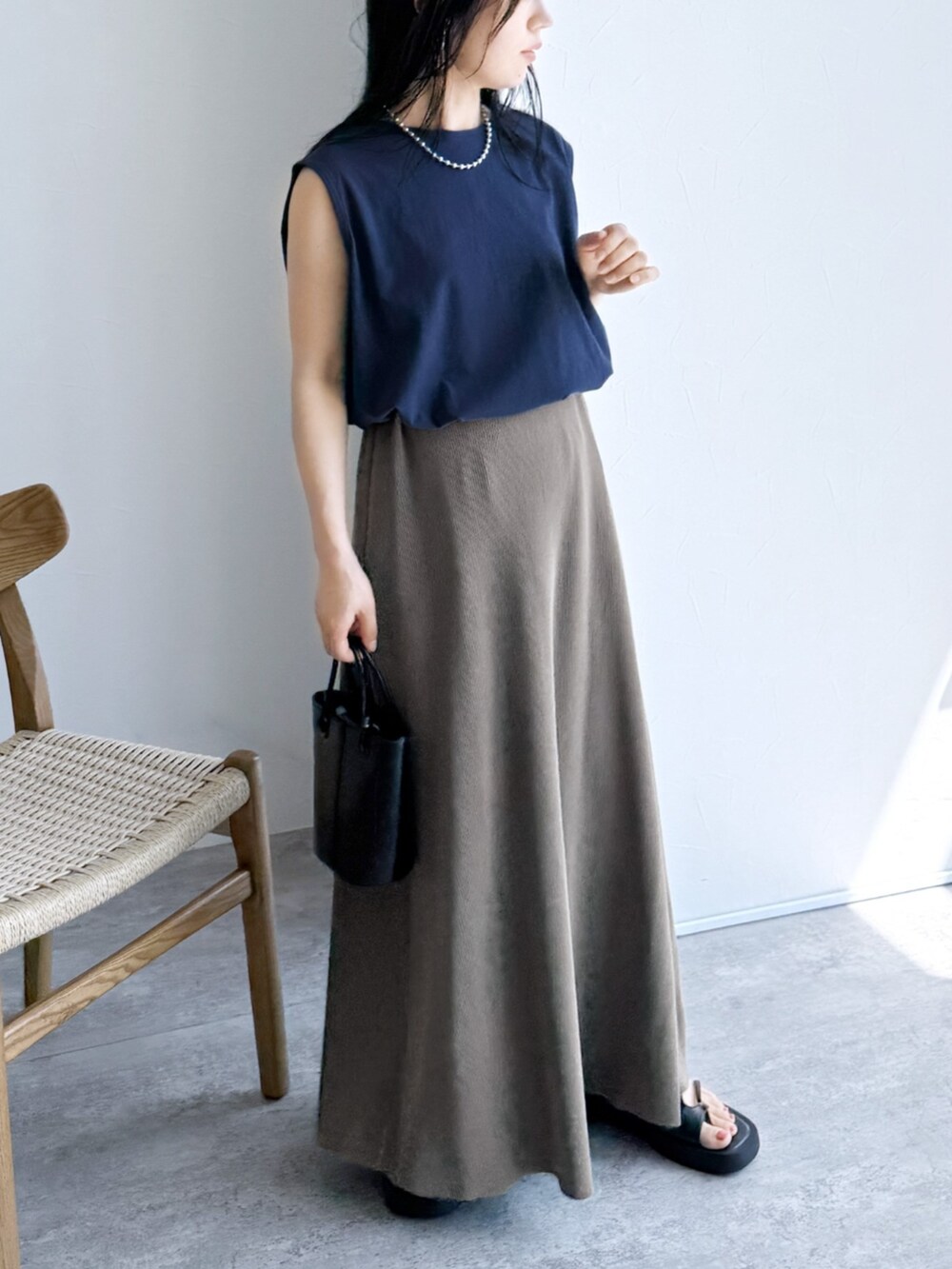 ベージュ系のスカート、ブルー系のタンクトップを着用したレディースの夏コーディネートの2枚目の写真