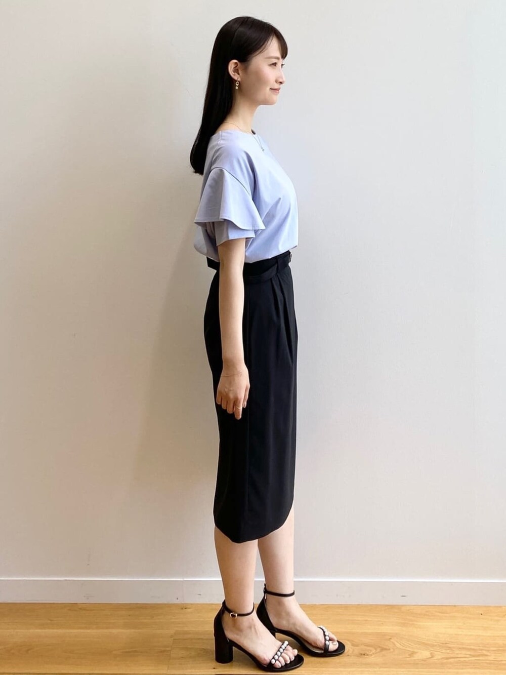 ブラック系のスカート、ブルー系のTシャツ/カットソー、ブラック系のサンダルを着用したレディースの春コーディネートの2枚目の写真