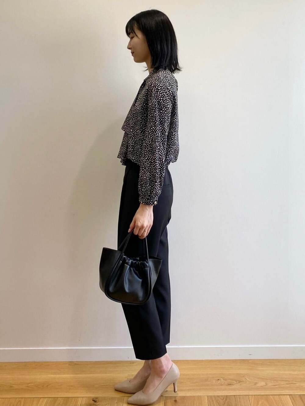 ブラック系のトートバッグ、ベージュ系のパンプス、ブラック系のその他パンツを着用したレディースの春コーディネートの2枚目の写真