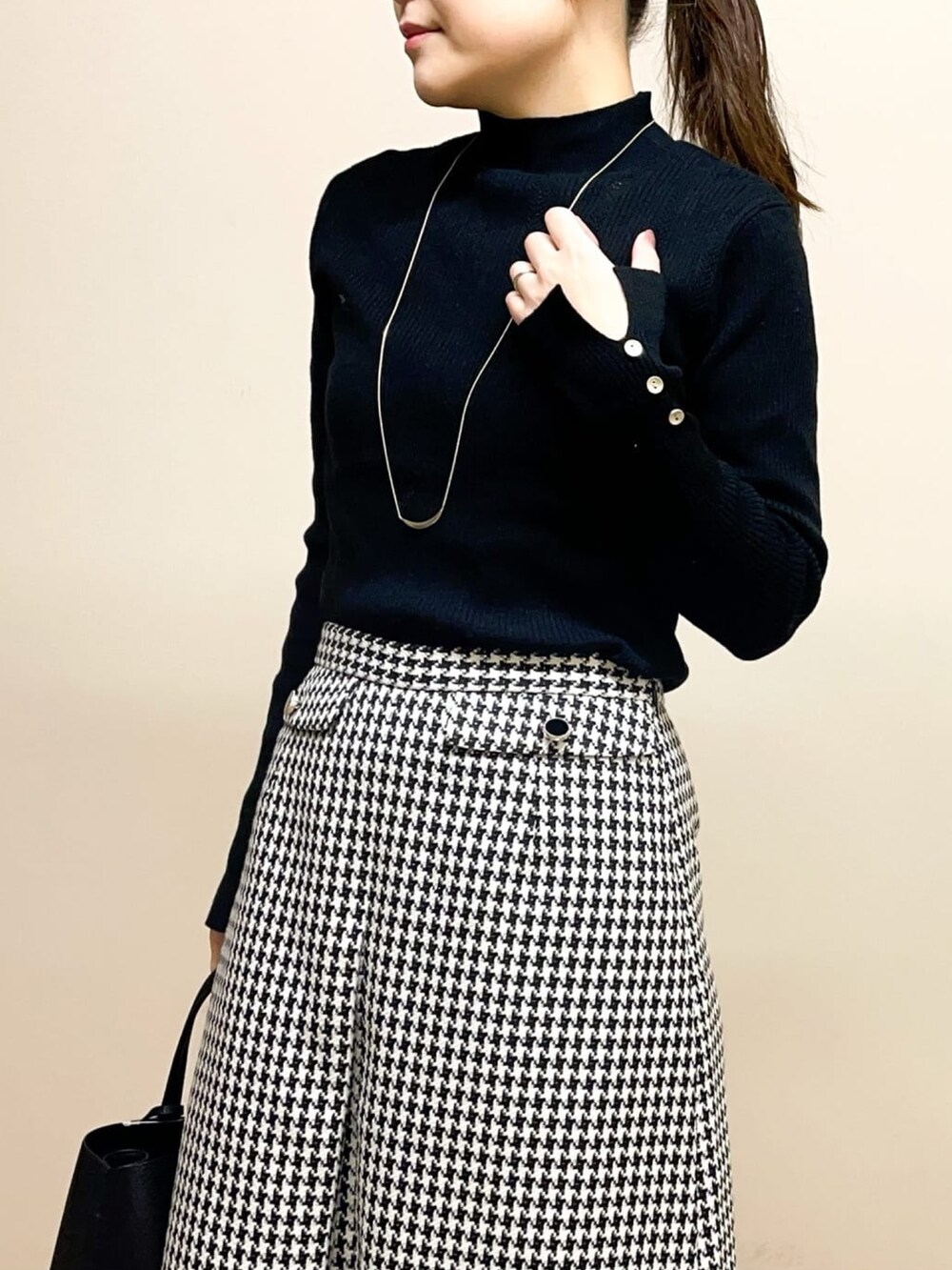 ベージュ系のノーカラーコート、ブラック系のニット/セーター、ブラック系のトートバッグを着用したレディースの冬コーディネートの4枚目の写真