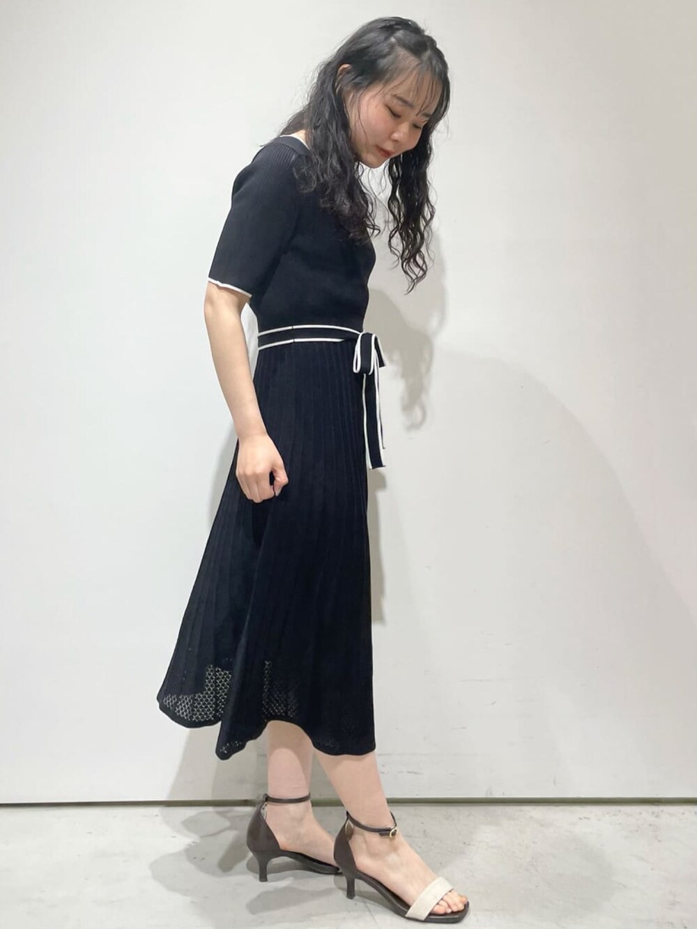 ブラック系のワンピース、グレー系のカーディガン/ボレロ、ベージュ系のサンダルを着用したレディースの春コーディネートの4枚目の写真