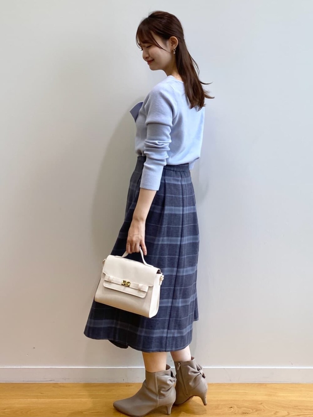 ブルー系のニット/セーター、グレー系のスカート、ホワイト系のショルダーバッグを着用したレディースの秋コーディネートの5枚目の写真