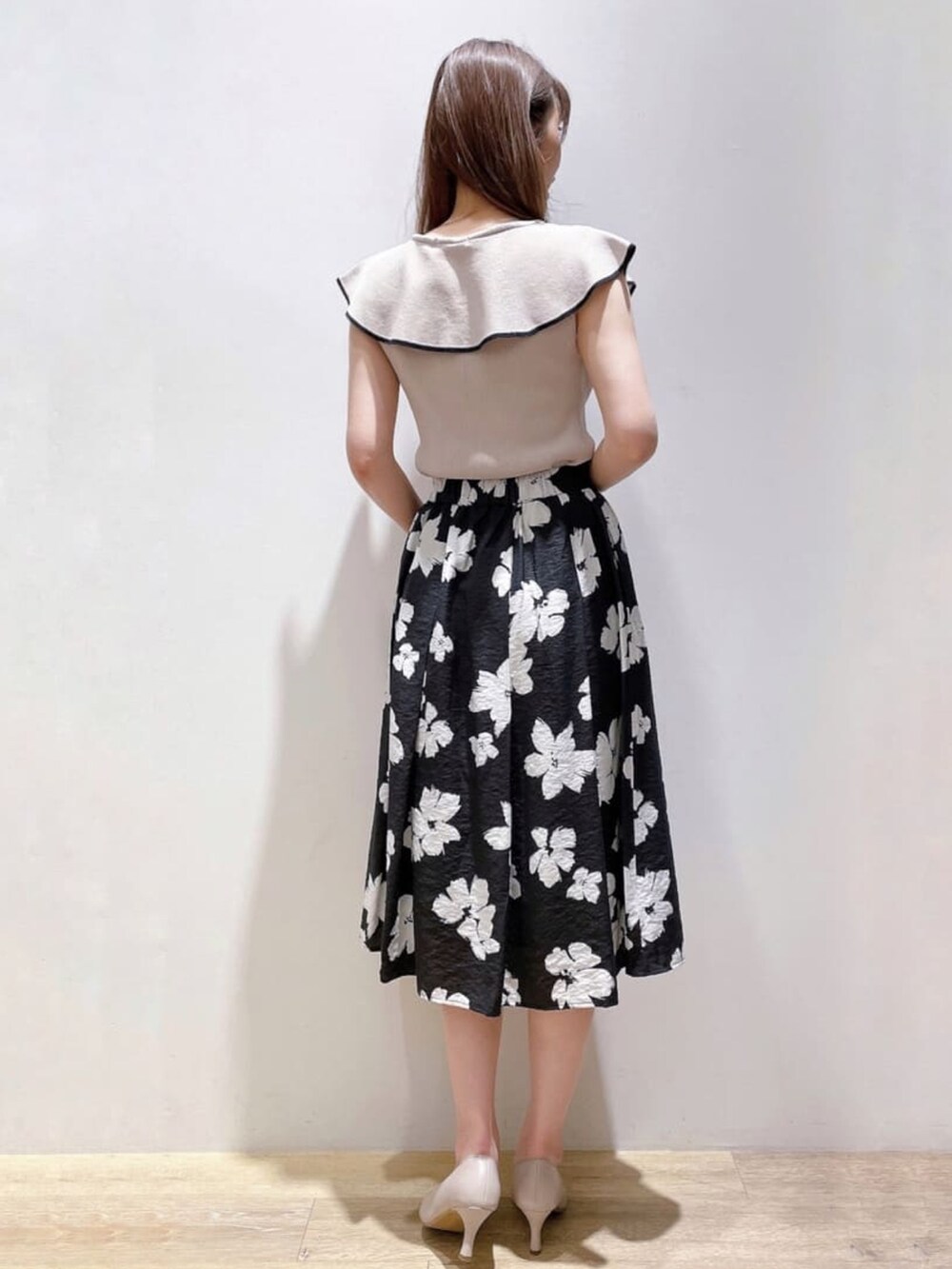 グレー系のニット/セーター、ブラック系のスカート、グレー系のパンプスを着用したレディースの春コーディネートの3枚目の写真