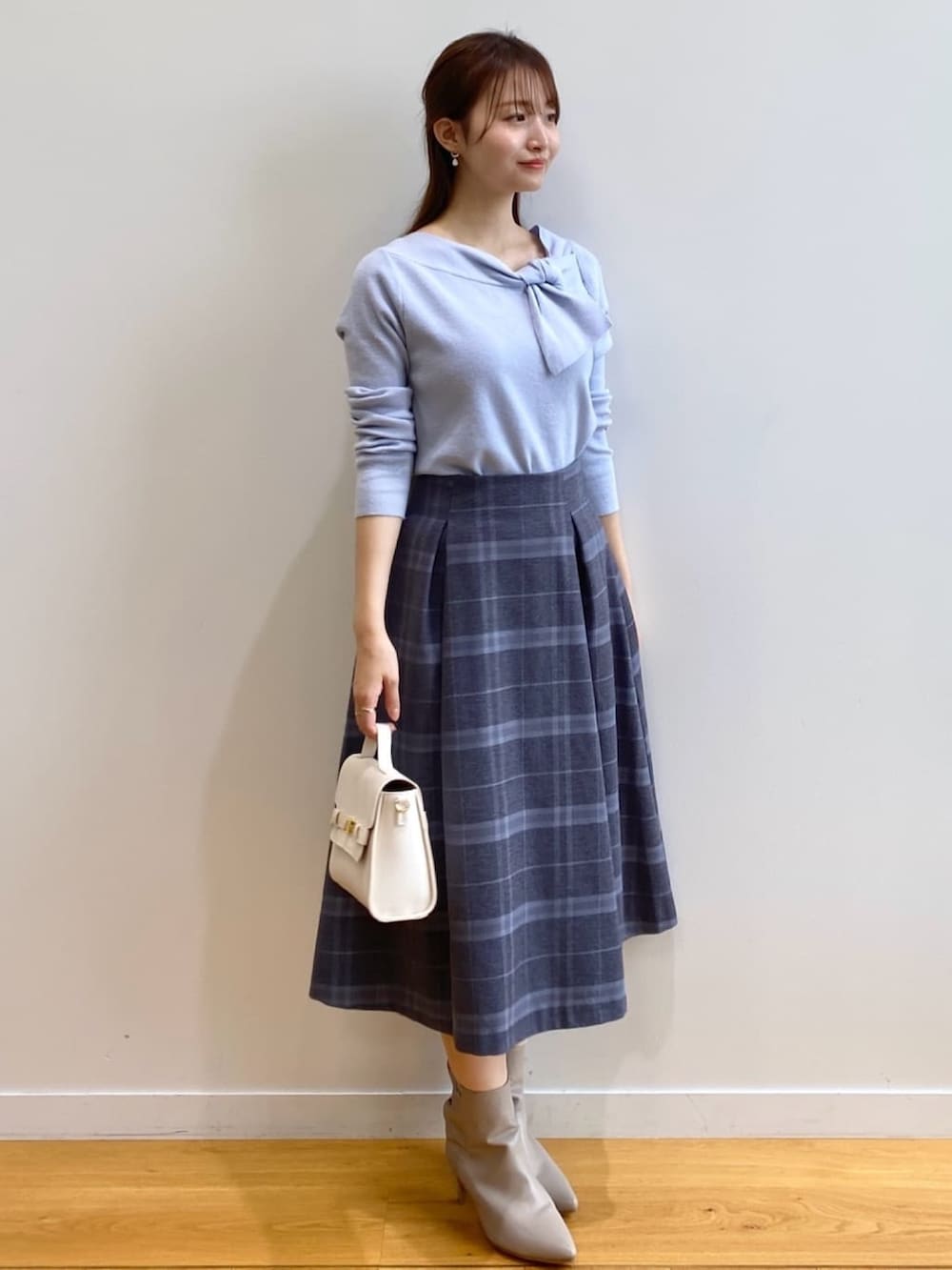 ブルー系のニット/セーター、グレー系のスカート、ホワイト系のショルダーバッグを着用したレディースの秋コーディネートの3枚目の写真