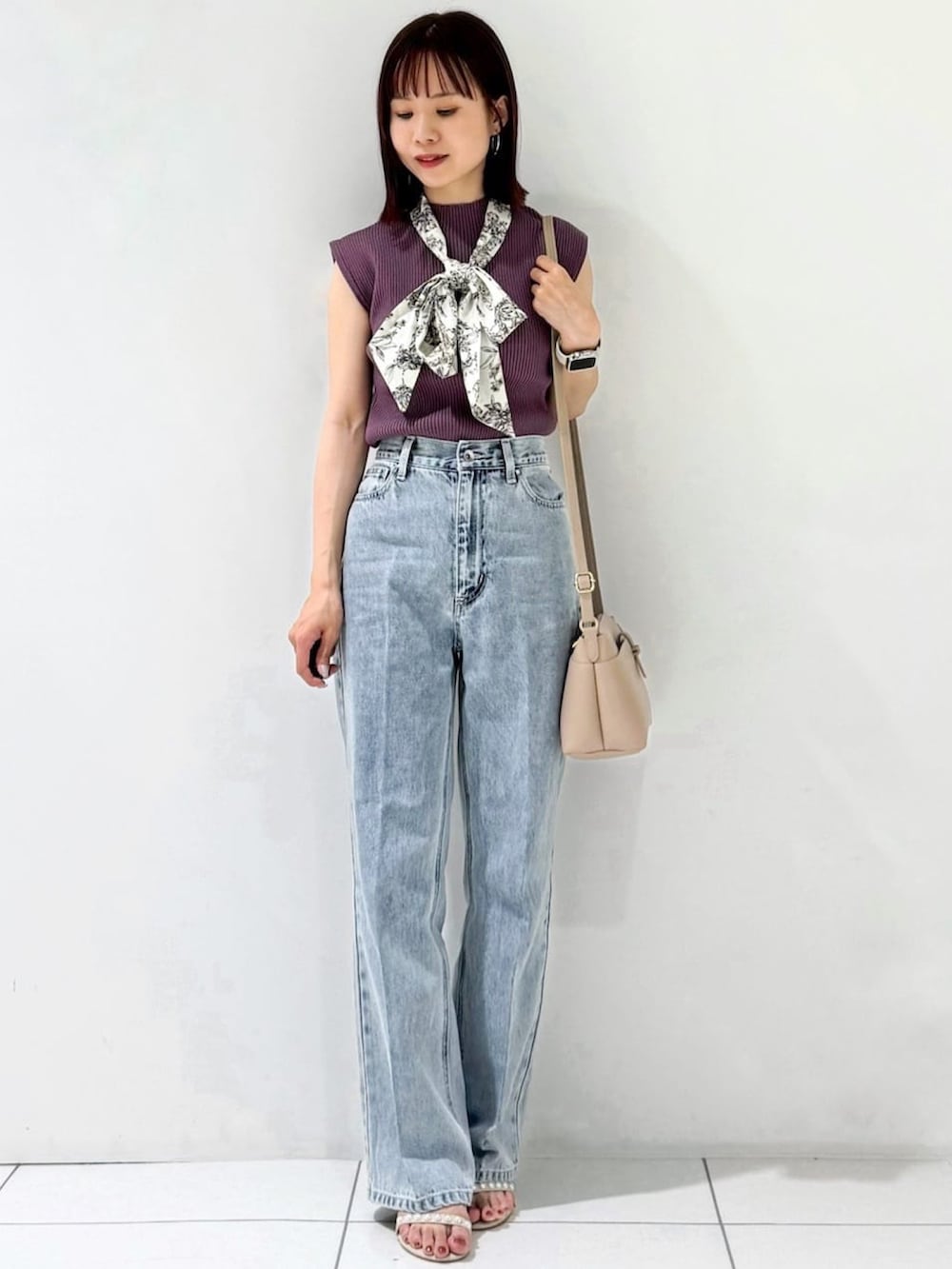 パープル系のニット/セーター、ベージュ系のショルダーバッグ、ブルー系のデニムパンツを着用したレディースの夏コーディネートの2枚目の写真