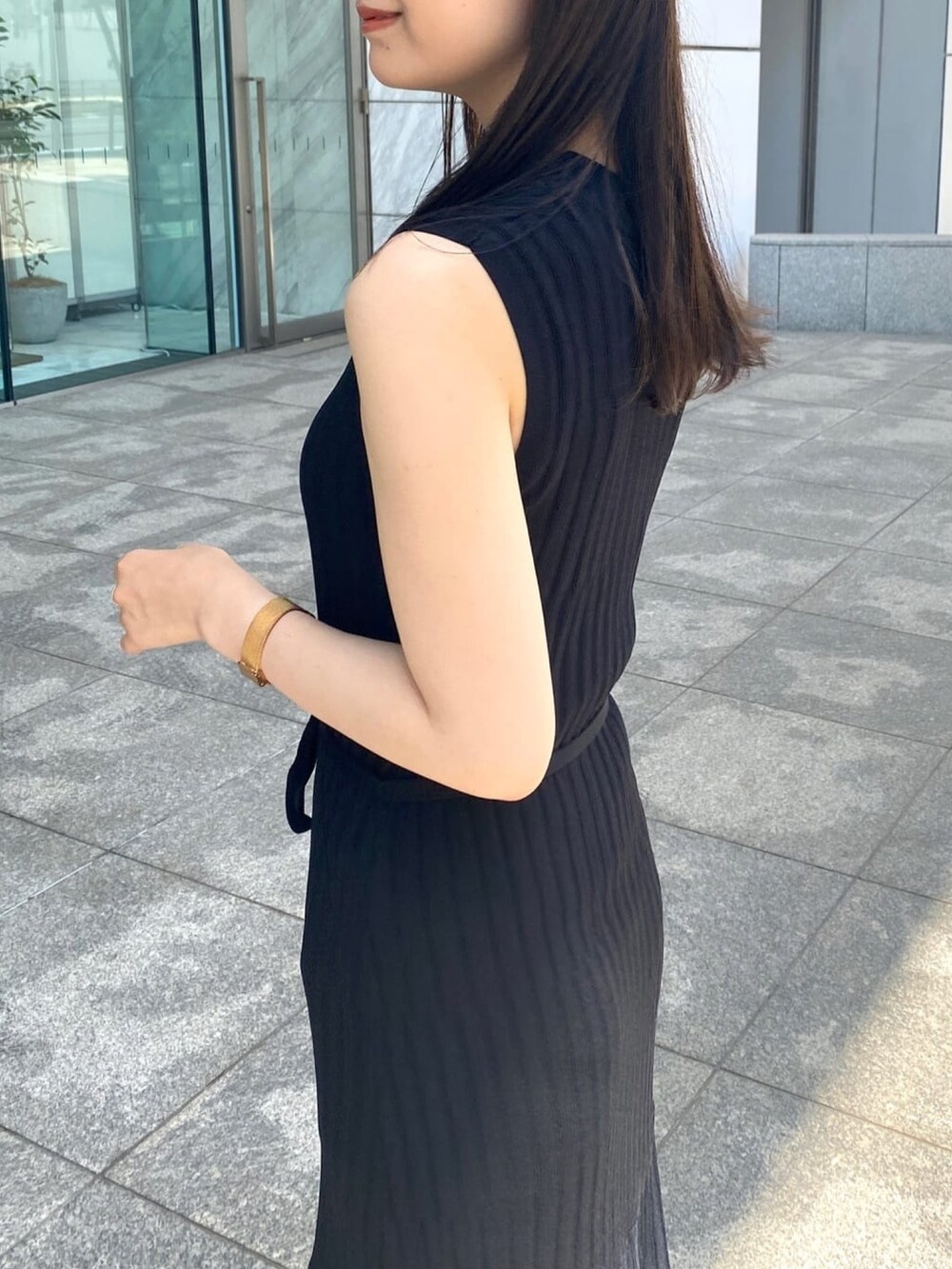 ブラック系のワンピース、ブラック系のパンプス、ゴールド系のピアス（両耳用）を着用したレディースの春コーディネートの5枚目の写真