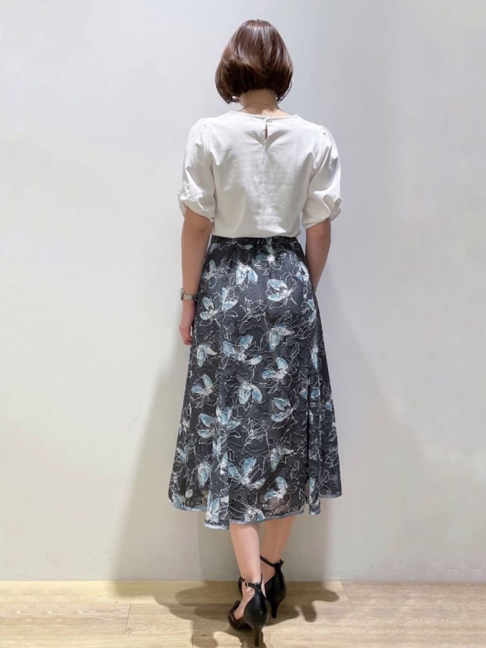 ブラック系のパンプス、グレー系のスカート、ホワイト系のTシャツ/カットソーを着用したレディースの夏コーディネートの3枚目の写真