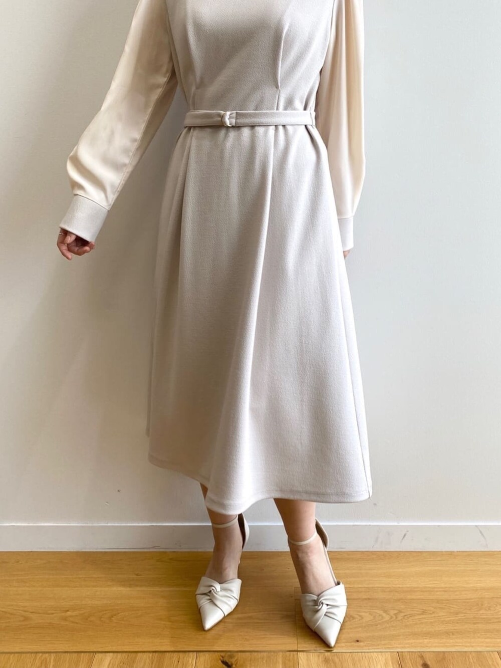 ベージュ系のワンピース、ホワイト系のパンプスを着用したレディースの冬コーディネートの8枚目の写真