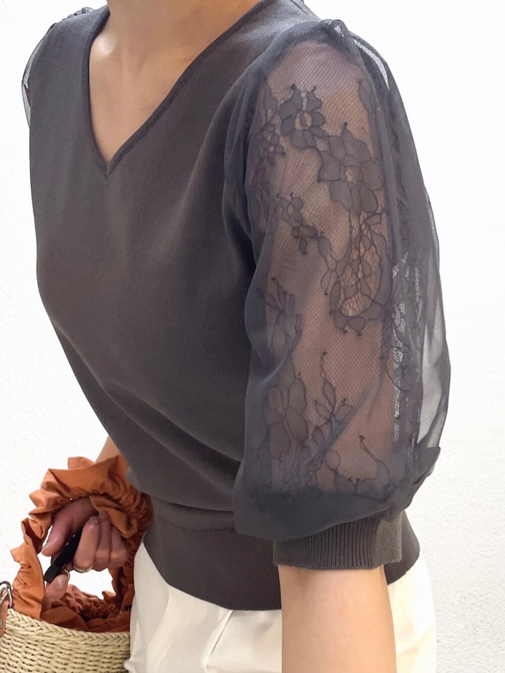 グレー系のニット/セーター、ホワイト系のその他パンツ、オレンジ系のショルダーバッグを着用したレディースの夏コーディネートの4枚目の写真