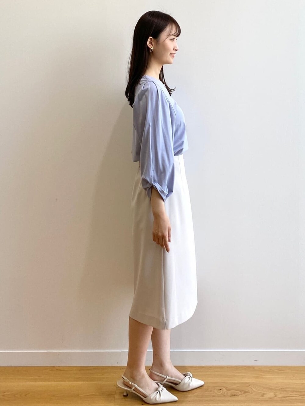 グレー系のスカート、ブルー系のTシャツ/カットソー、ホワイト系のパンプスを着用したレディースの春コーディネートの2枚目の写真