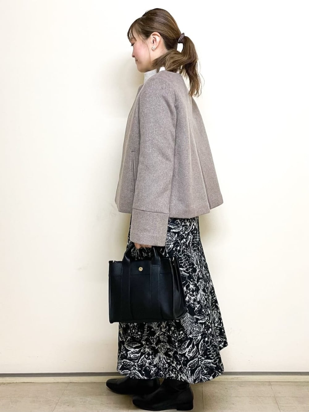 ベージュ系のニット/セーター、ブラック系のスカート、ブラック系のトートバッグを着用したレディースの冬コーディネートの3枚目の写真