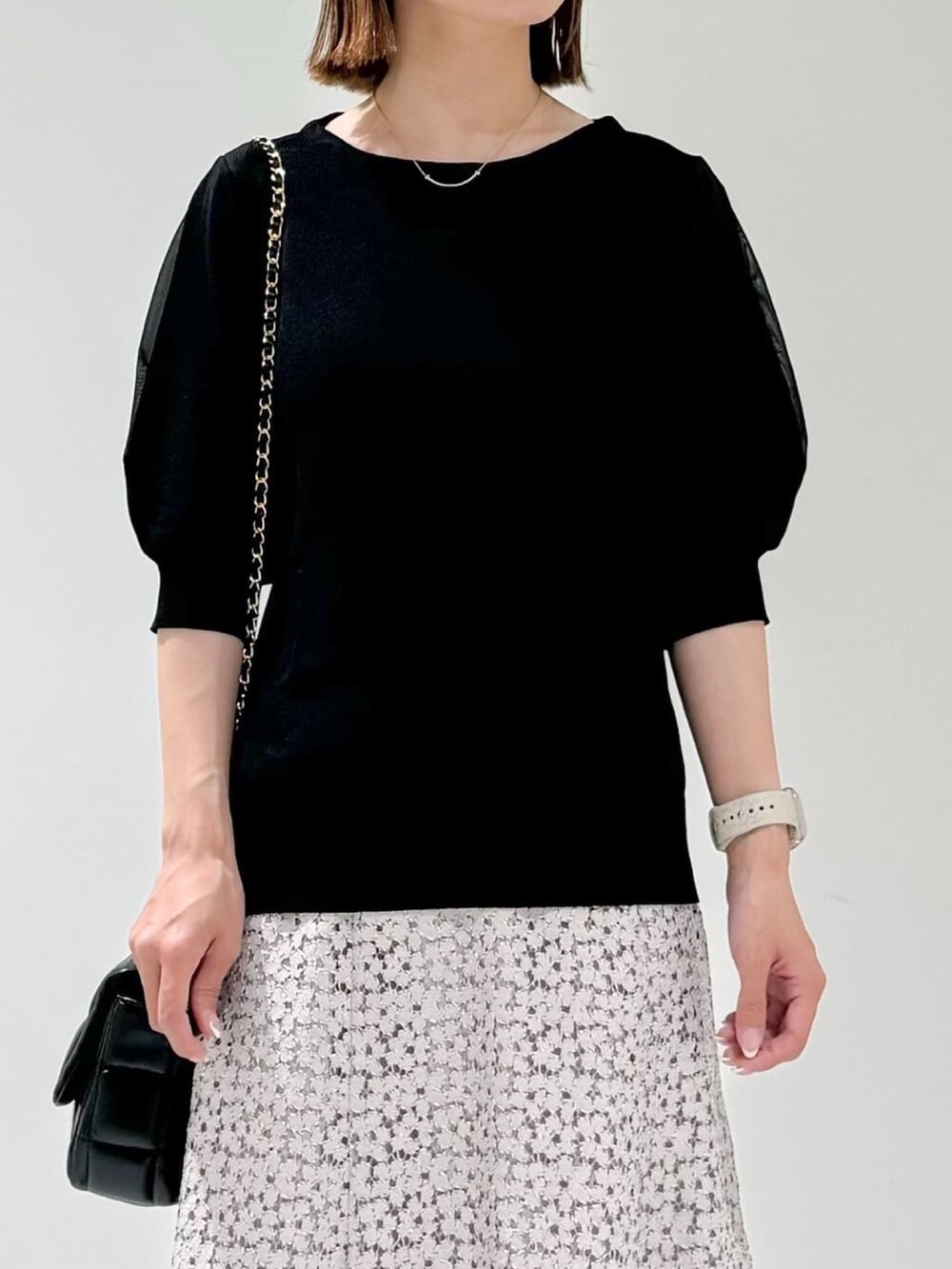 ブラック系のニット/セーター、ベージュ系のサンダル、ベージュ系のスカートを着用したレディースの夏コーディネートの2枚目の写真