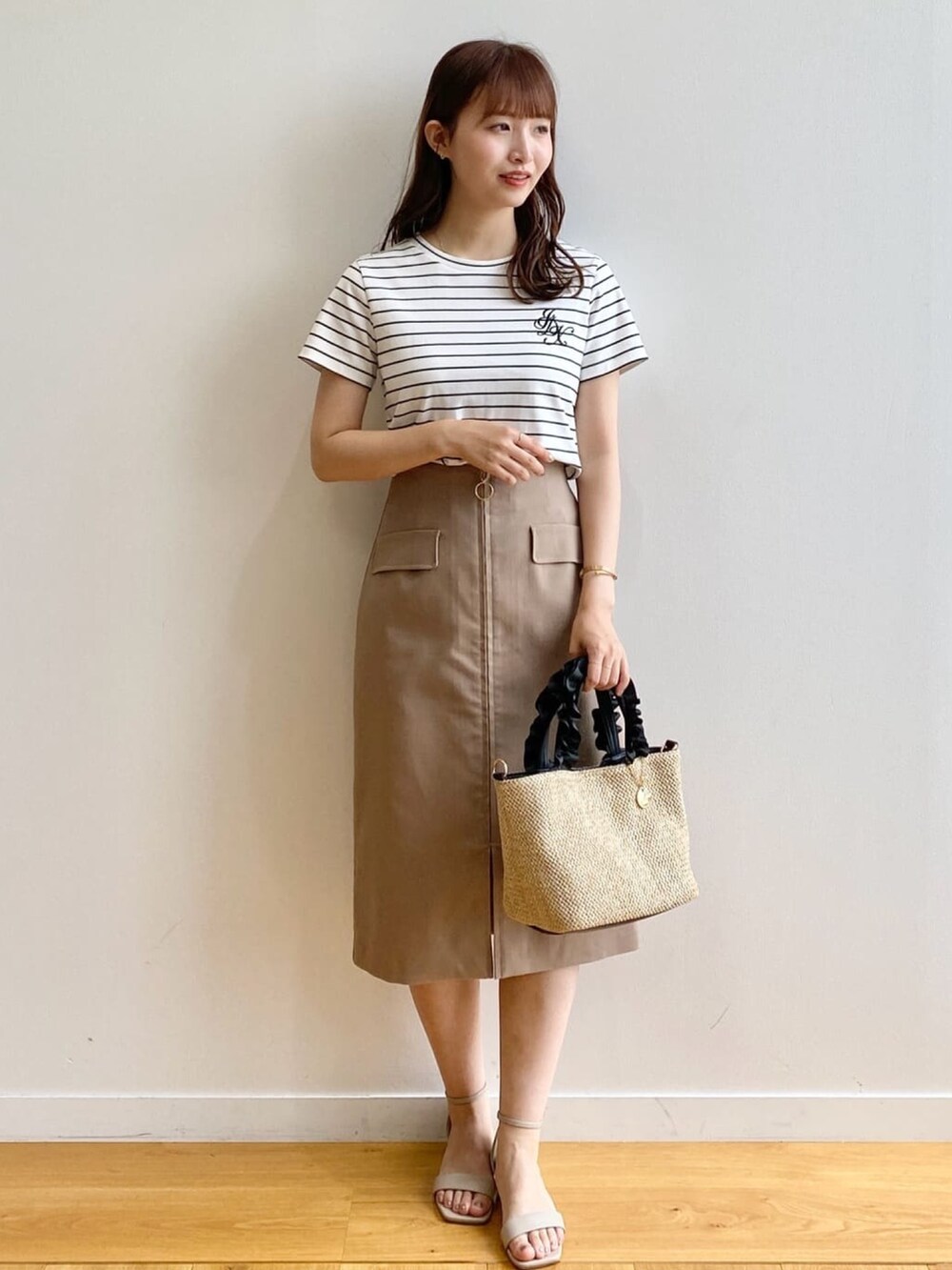 ホワイト系のTシャツ/カットソー、ブラウン系のスカート、ブラック系のトートバッグを着用したレディースの夏コーディネートの2枚目の写真