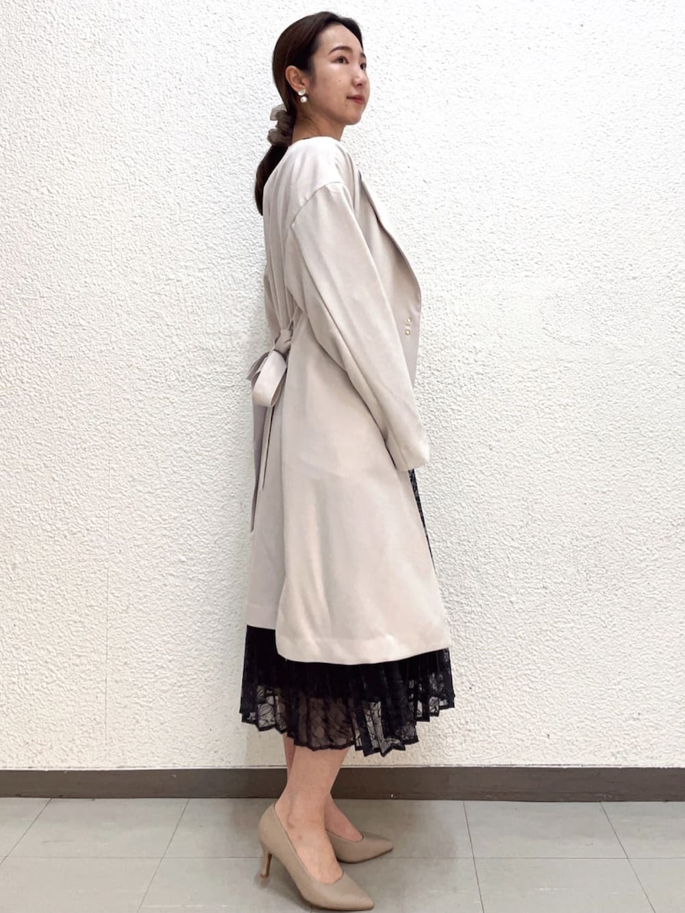 ブラック系のワンピース、ベージュ系のノーカラーコート、ベージュ系のパンプスを着用したレディースの春コーディネートの2枚目の写真