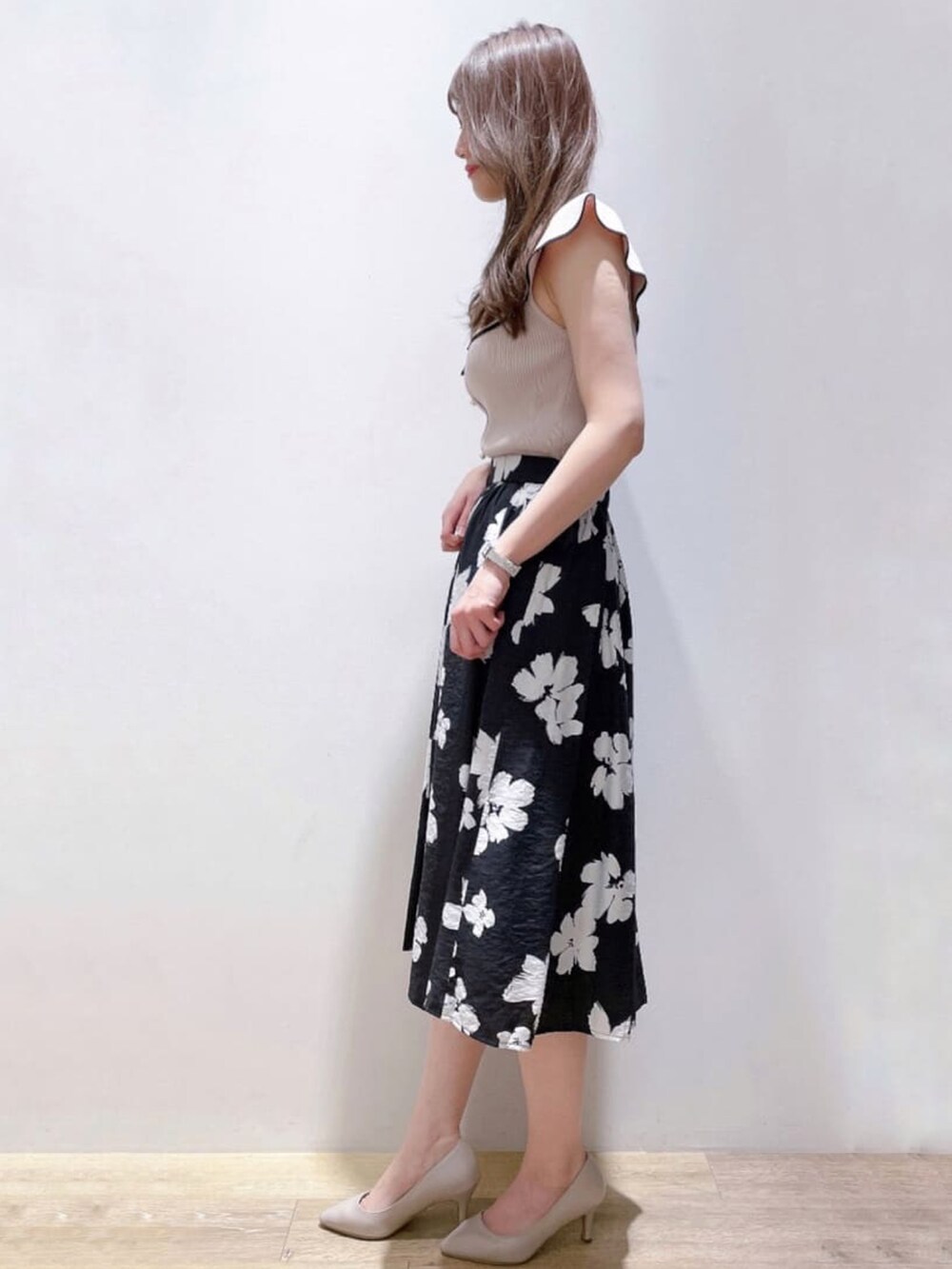 グレー系のニット/セーター、ブラック系のスカート、グレー系のパンプスを着用したレディースの春コーディネートの2枚目の写真