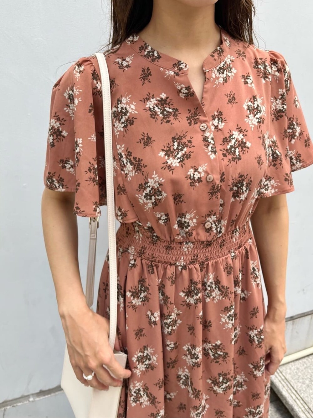 オレンジ系のワンピース、ホワイト系のショルダーバッグ、ホワイト系のパンプスを着用したレディースの夏コーディネートの4枚目の写真