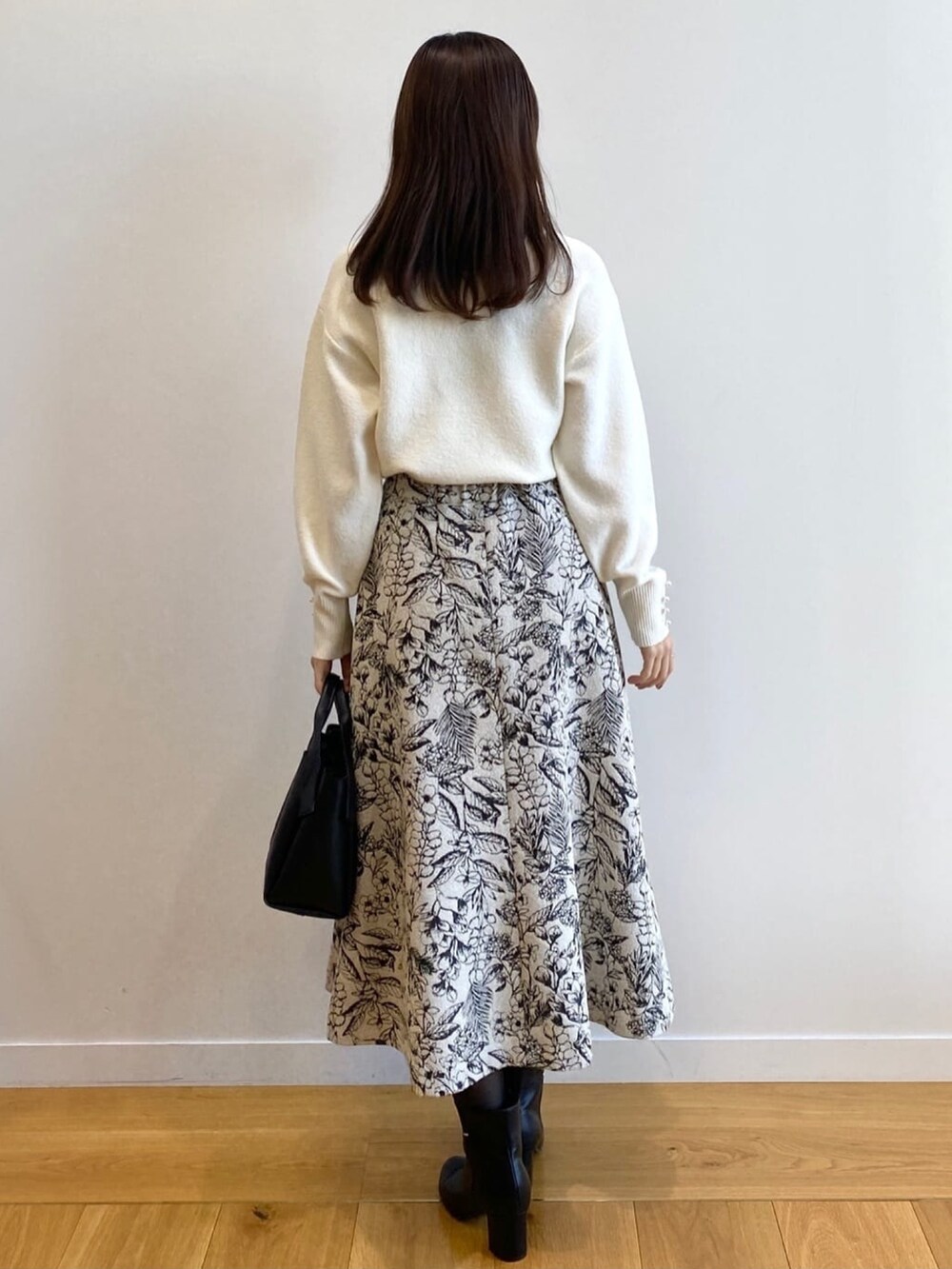 ホワイト系のニット/セーター、ブラック系のショルダーバッグ、ブラック系のブーツを着用したレディースの冬コーディネートの3枚目の写真