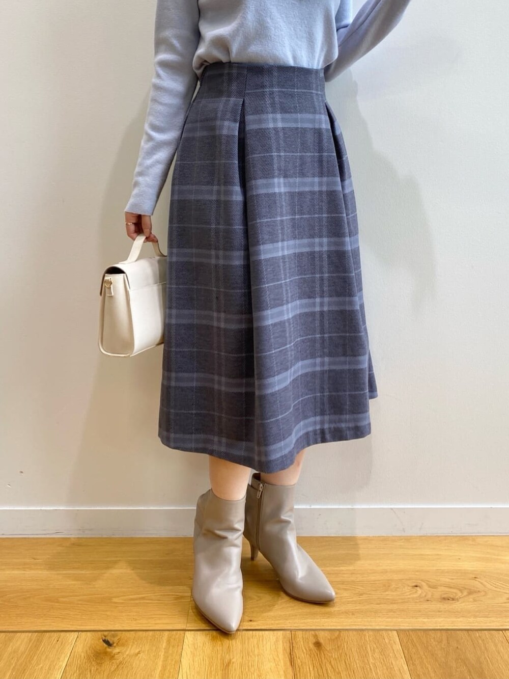 ブルー系のニット/セーター、グレー系のスカート、ホワイト系のショルダーバッグを着用したレディースの秋コーディネートの10枚目の写真