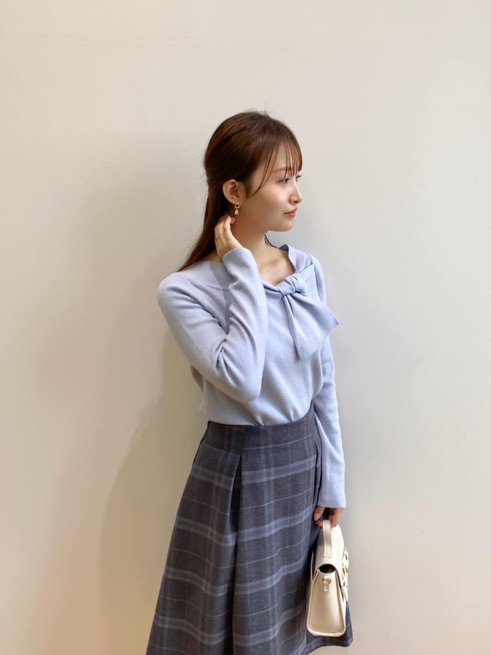 ブルー系のニット/セーター、グレー系のスカート、ホワイト系のショルダーバッグを着用したレディースの秋コーディネートの7枚目の写真