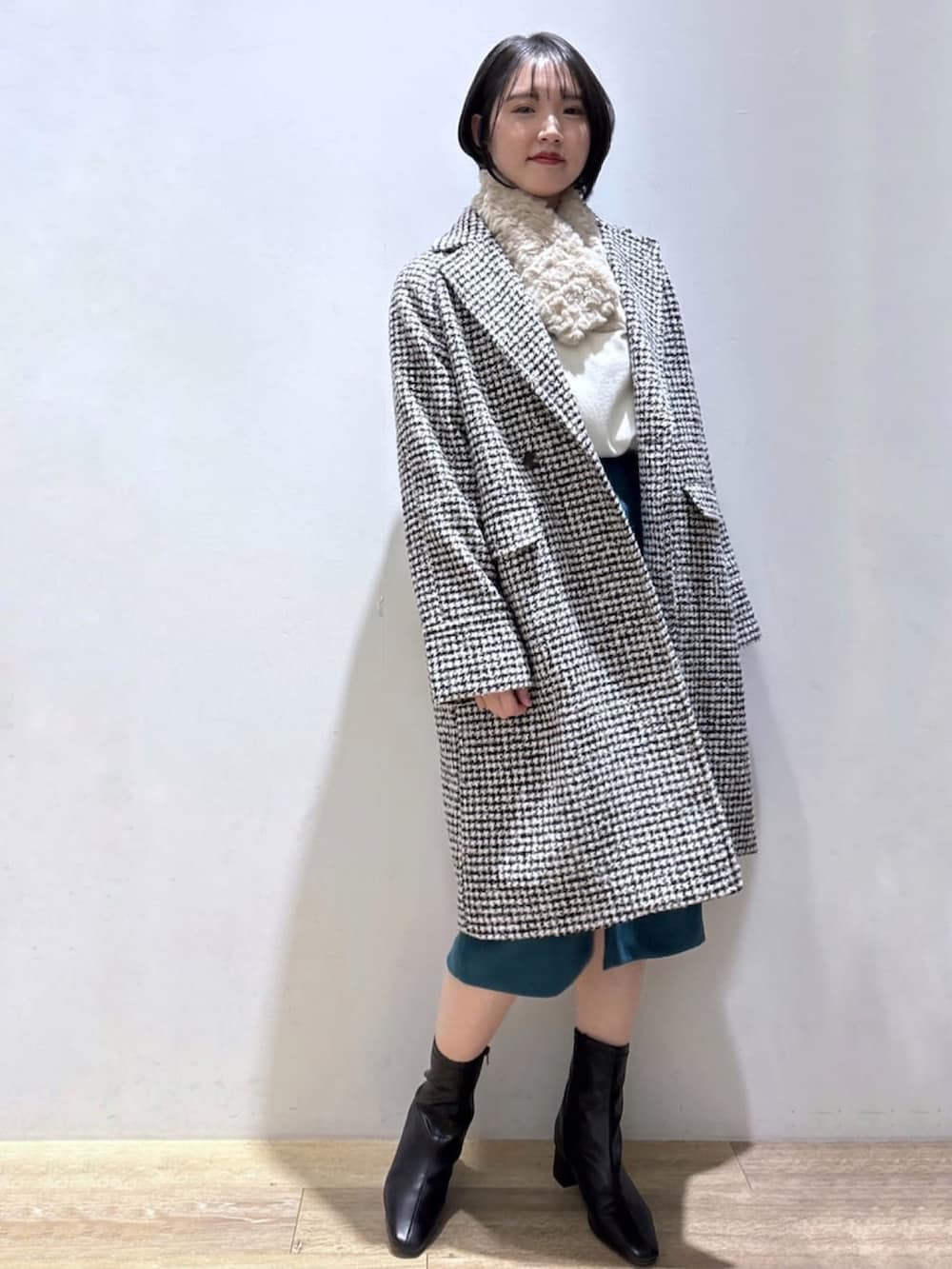 ベージュ系のニット/セーター、ブラック系のチェスターコート、ブルー系のスカートを着用したレディースの冬コーディネートの2枚目の写真