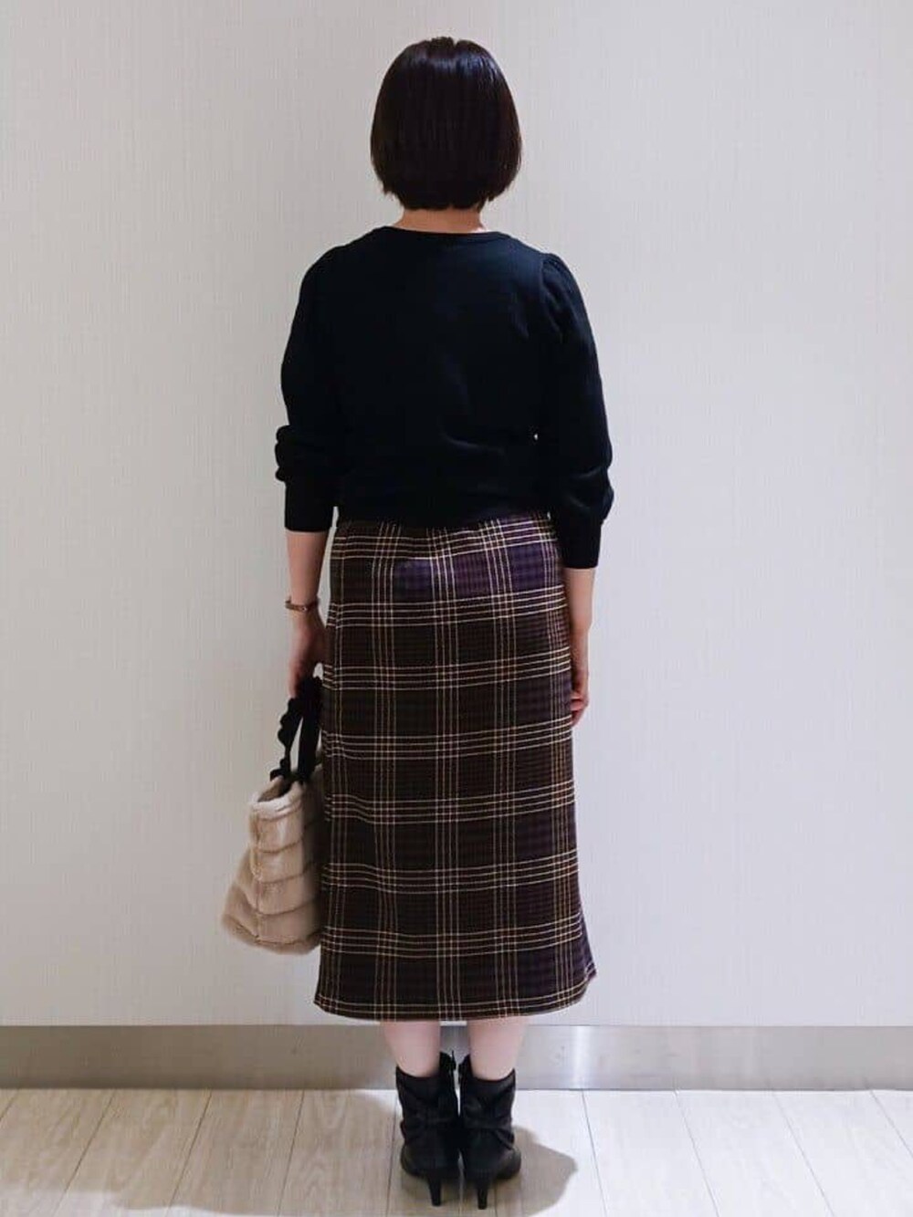 ブラック系のカーディガン/ボレロ、ブラウン系のスカート、ブラック系のブーツを着用したレディースの秋コーディネートの3枚目の写真