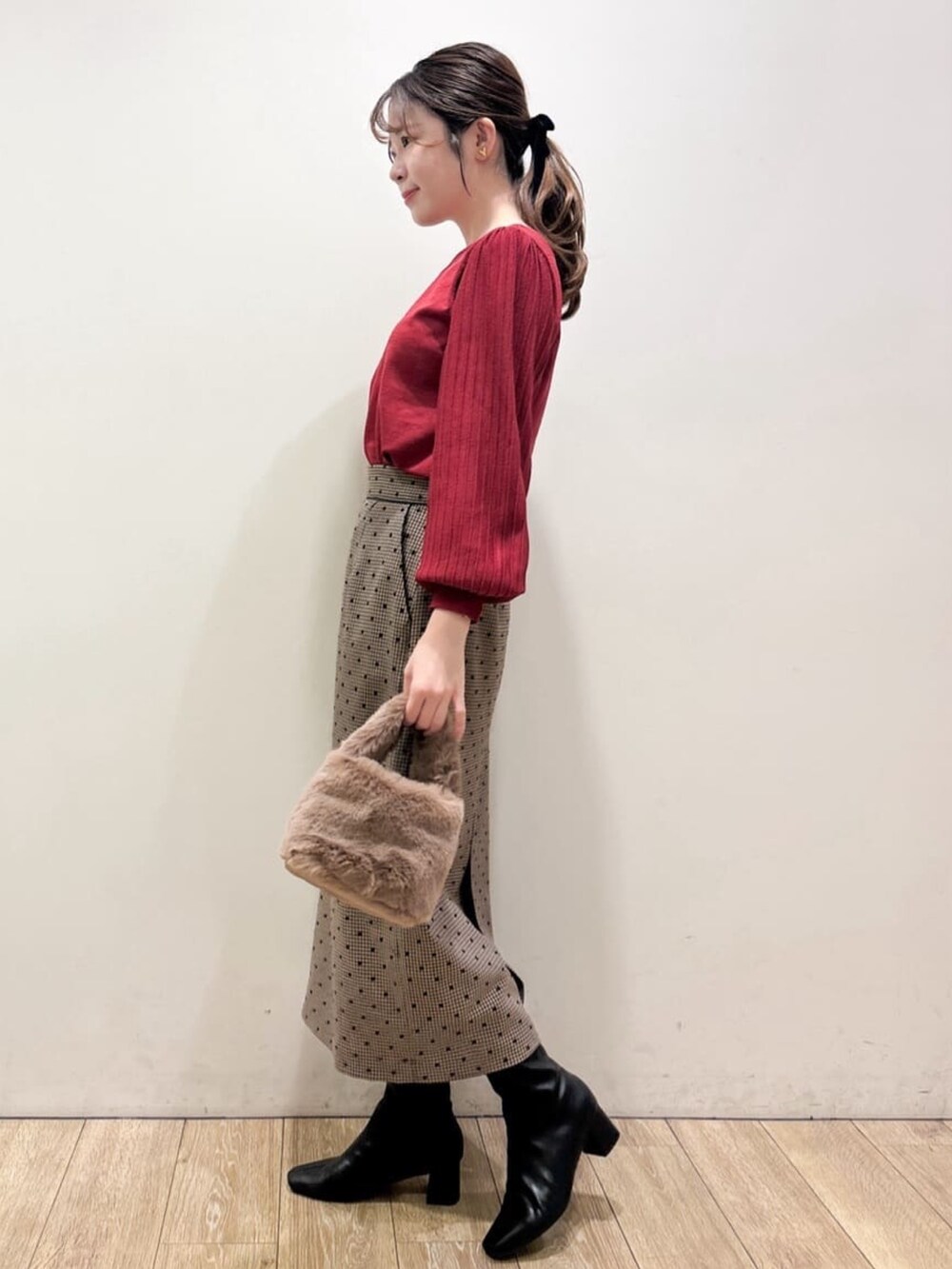 レッド系のニット/セーター、ブラウン系のスカート、ブラウン系のショルダーバッグを着用したレディースの秋コーディネートの3枚目の写真